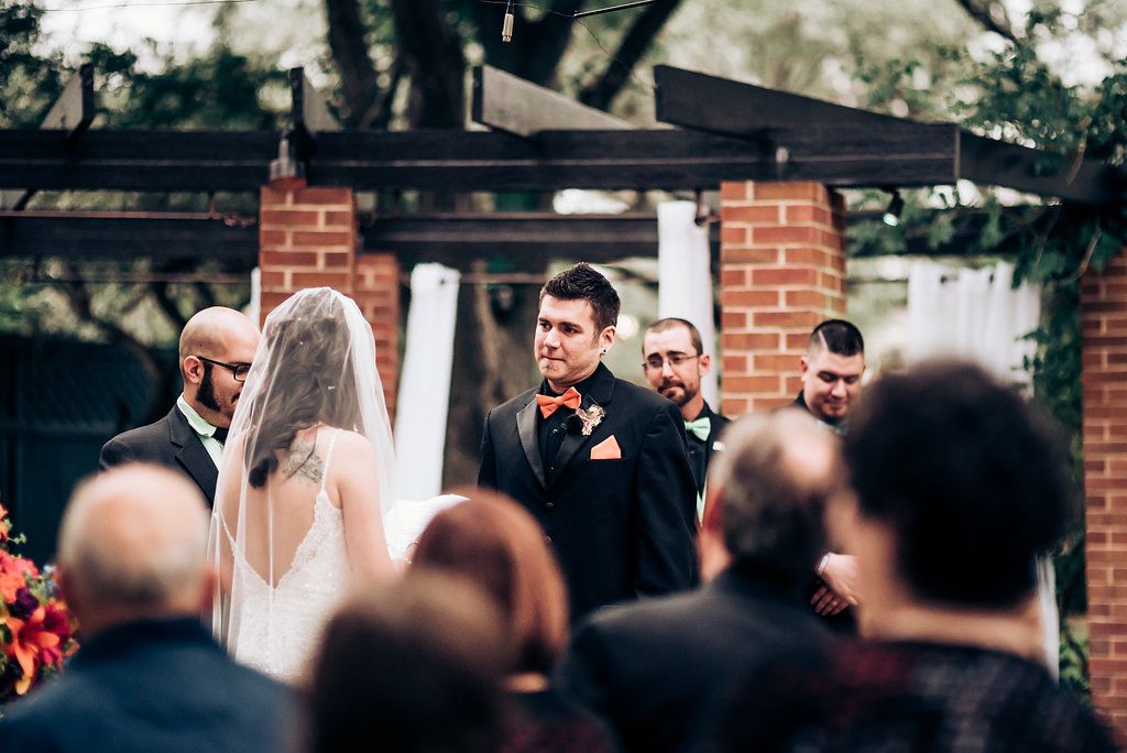 Couple exchanging vows at outdoor wedding venue framed by brick architecture.