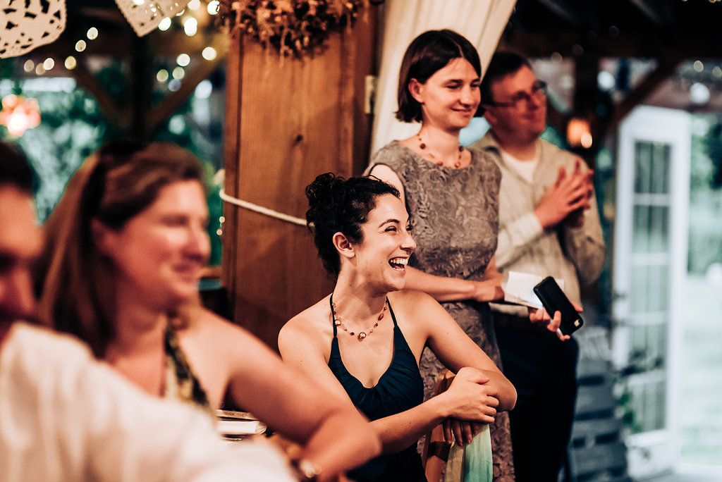 Guests enjoying themselves at a wedding reception with string lights and rustic decor.