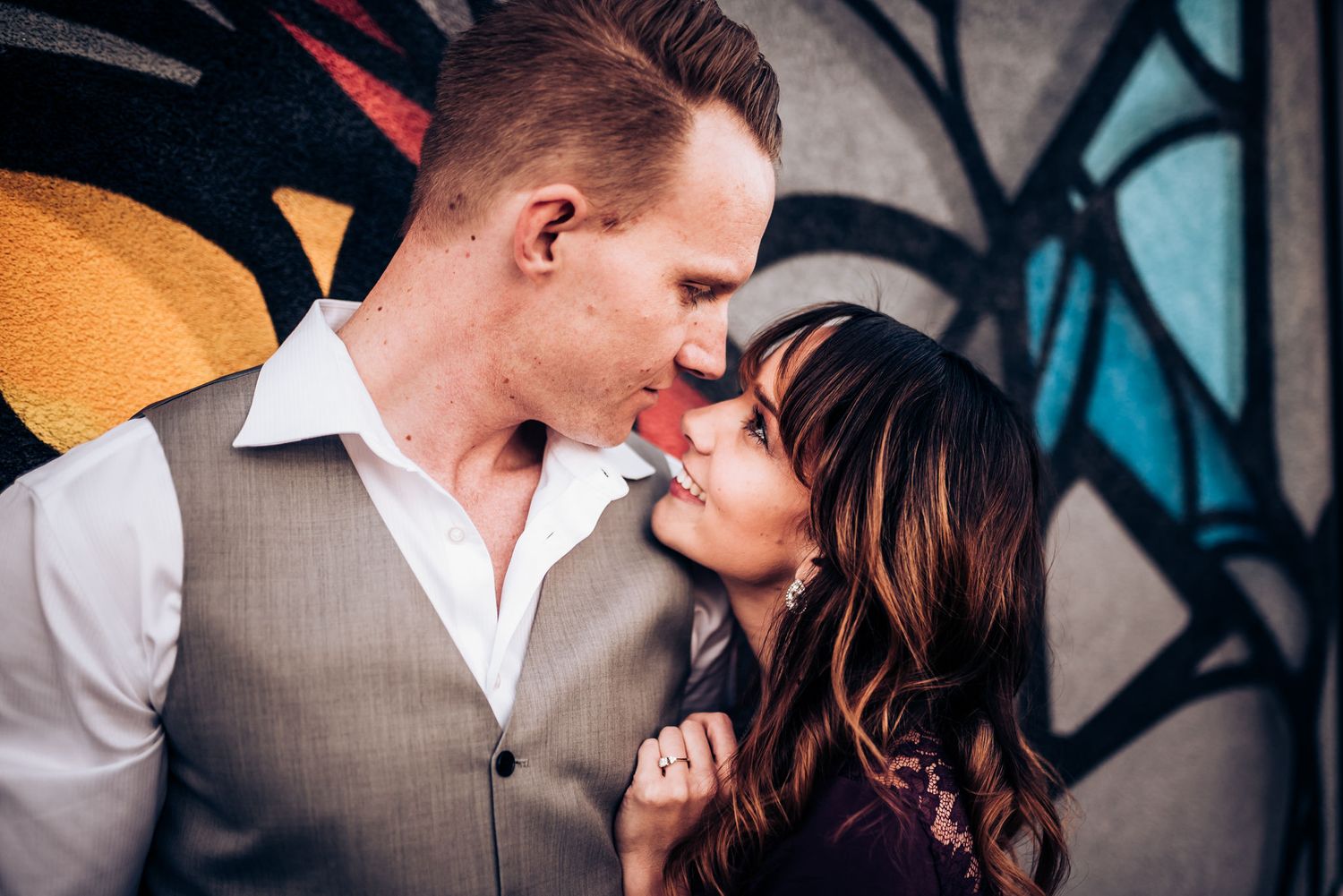 Romantic couple sharing an intimate moment against colorful street art background.