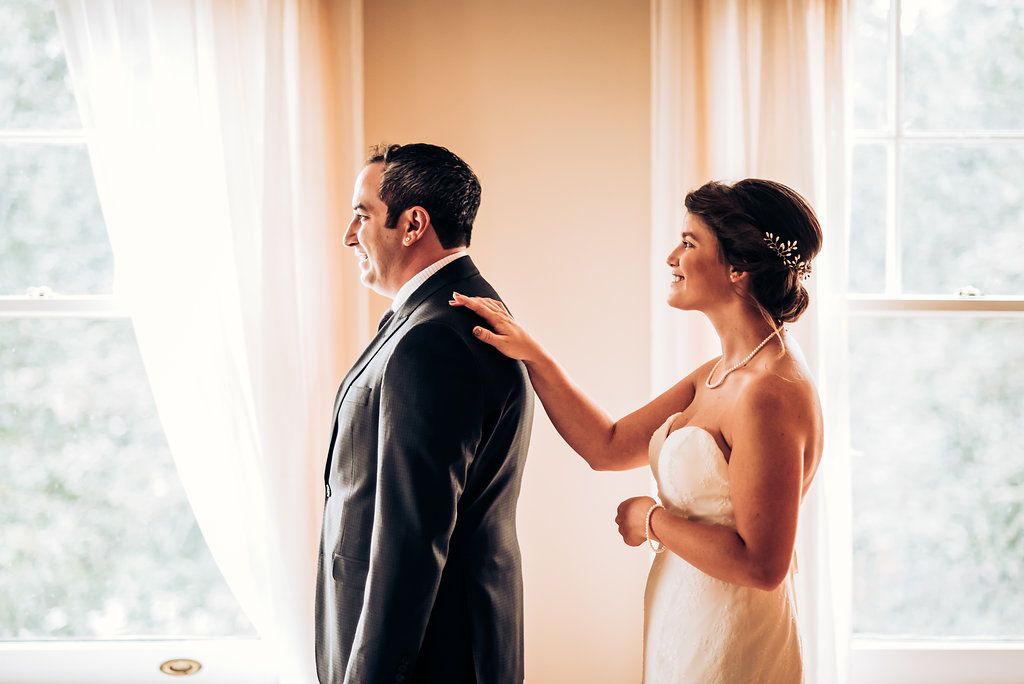 A touching first look moment between newlyweds by bright windows.