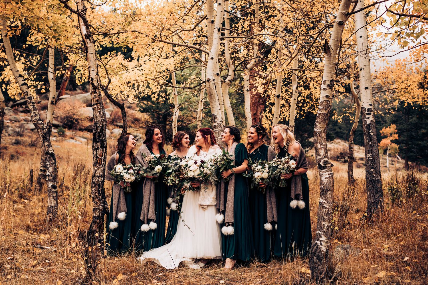 Wedding party poses among golden aspen trees in autumn mountain setting.