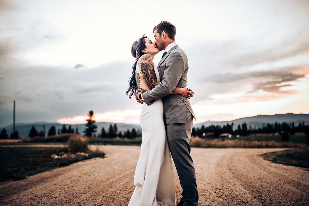 Dramatic sunset wedding portrait on a rural road with mountain backdrop.