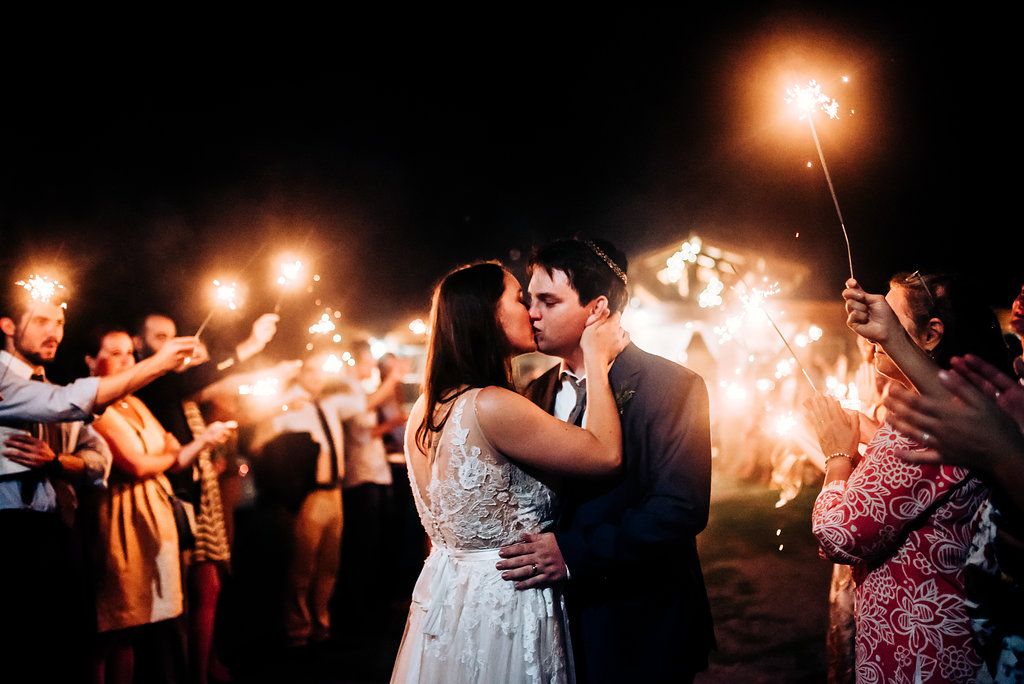 Intimate moment between couple during sparkler exit celebration at outdoor wedding reception.
