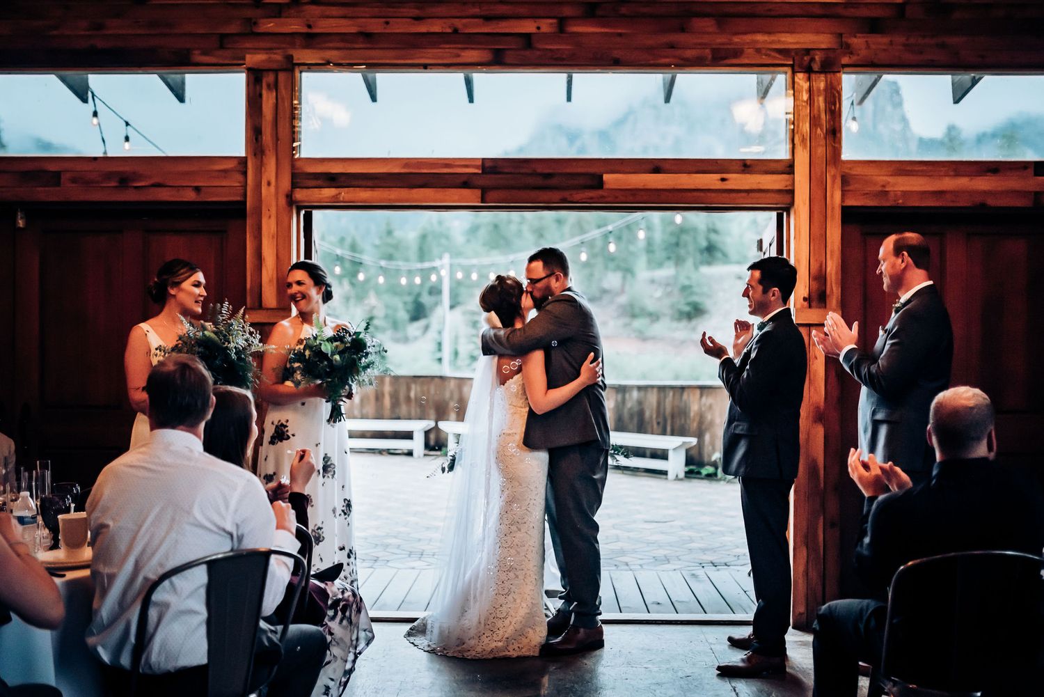 Wedding couple shares their first dance in a rustic wooden venue surrounded by guests.