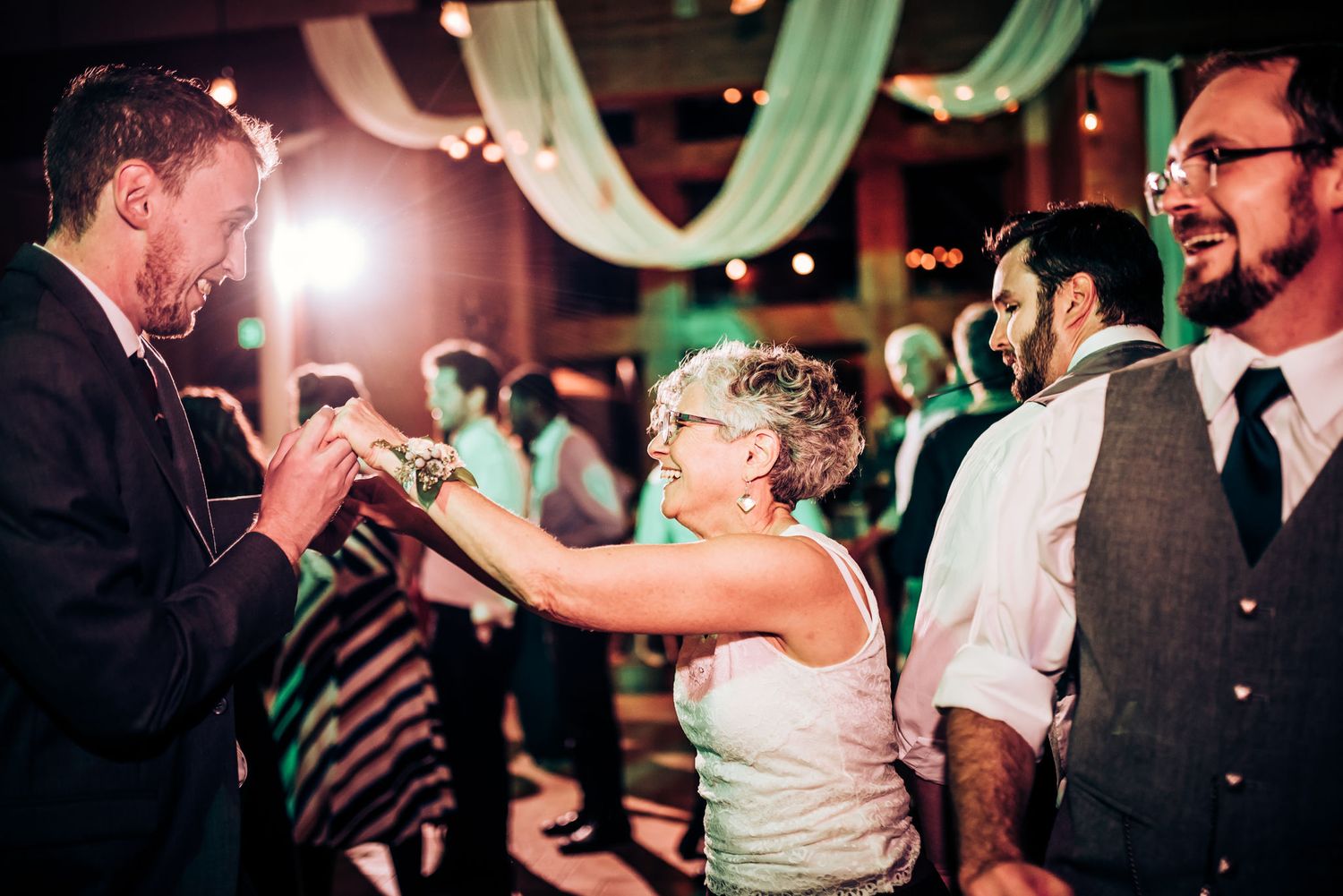 Dynamic dance floor moment between guests during a lively wedding reception celebration.