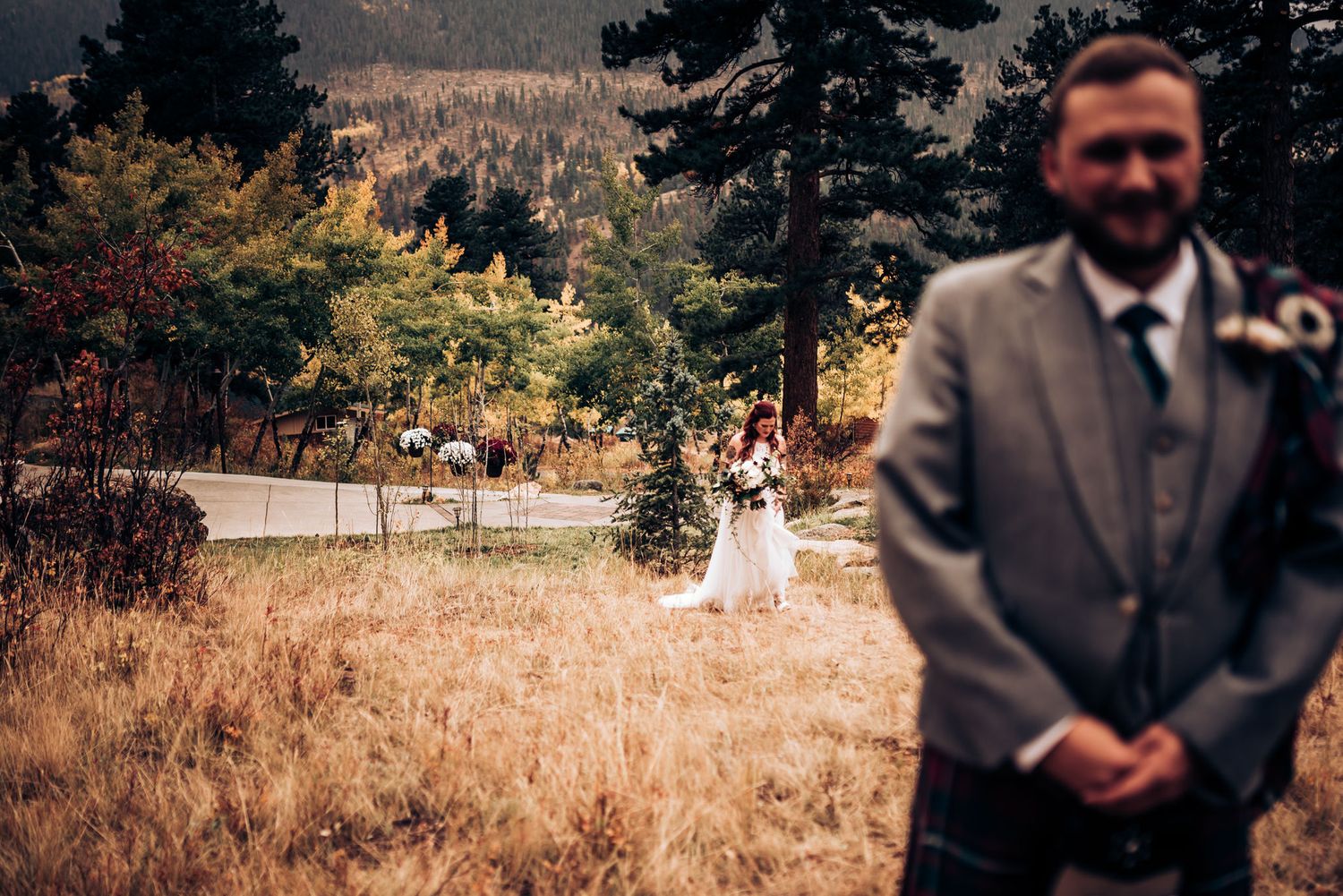 Autumn mountain wedding scene with tall pines and golden grass.