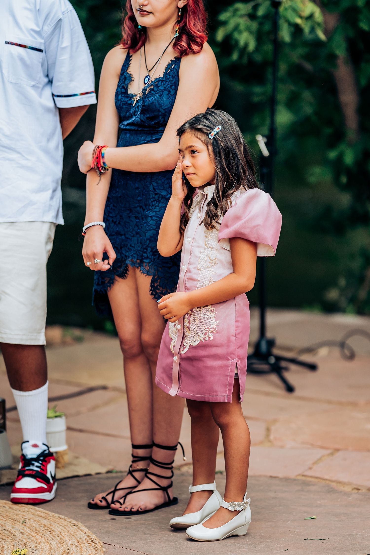 Two attendees in coordinating navy and pink outfits share an emotional moment during the ceremony.
