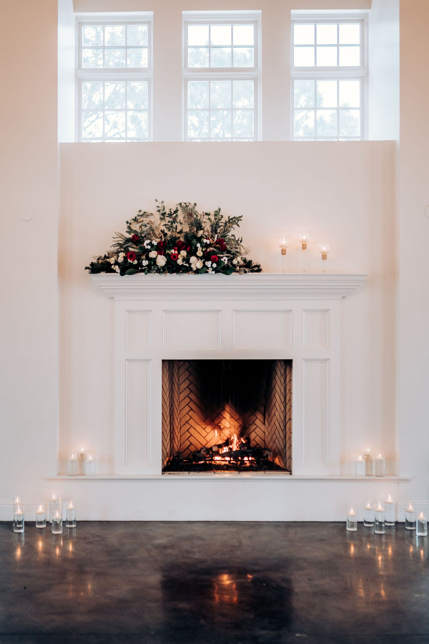 White fireplace with floral arrangement and candles in an elegant wedding venue.