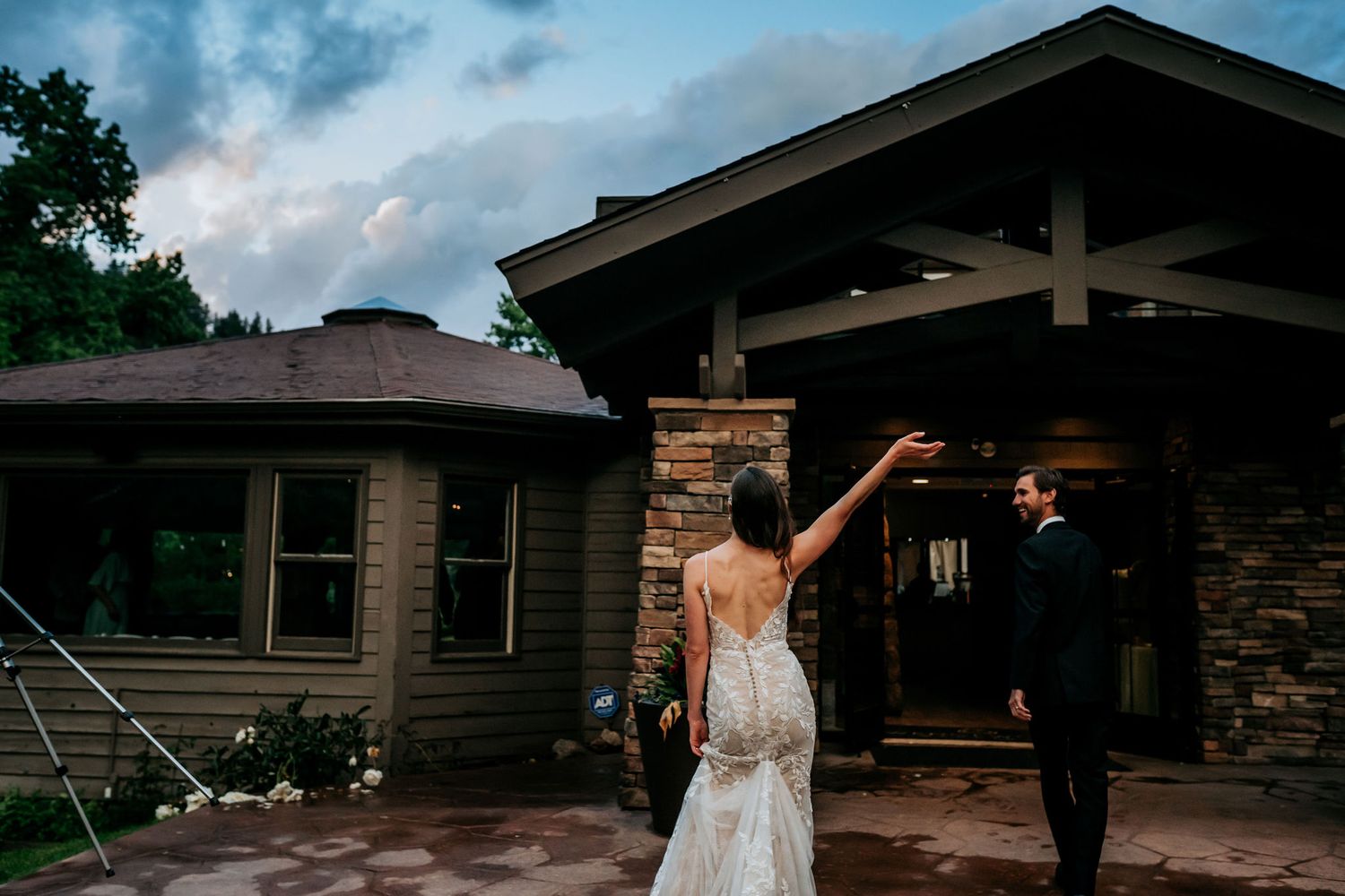 A couple celebrates outside a rustic stone and wood building at twilight.