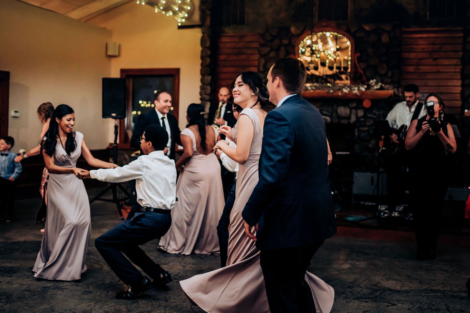 Wedding guests dancing and celebrating on the dance floor at an indoor reception venue.