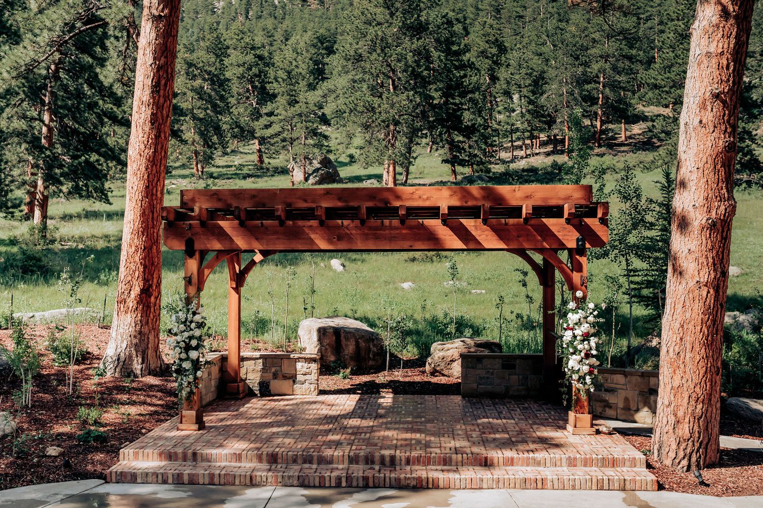 Rustic wooden pergola decorated for wedding ceremony in mountain forest setting.