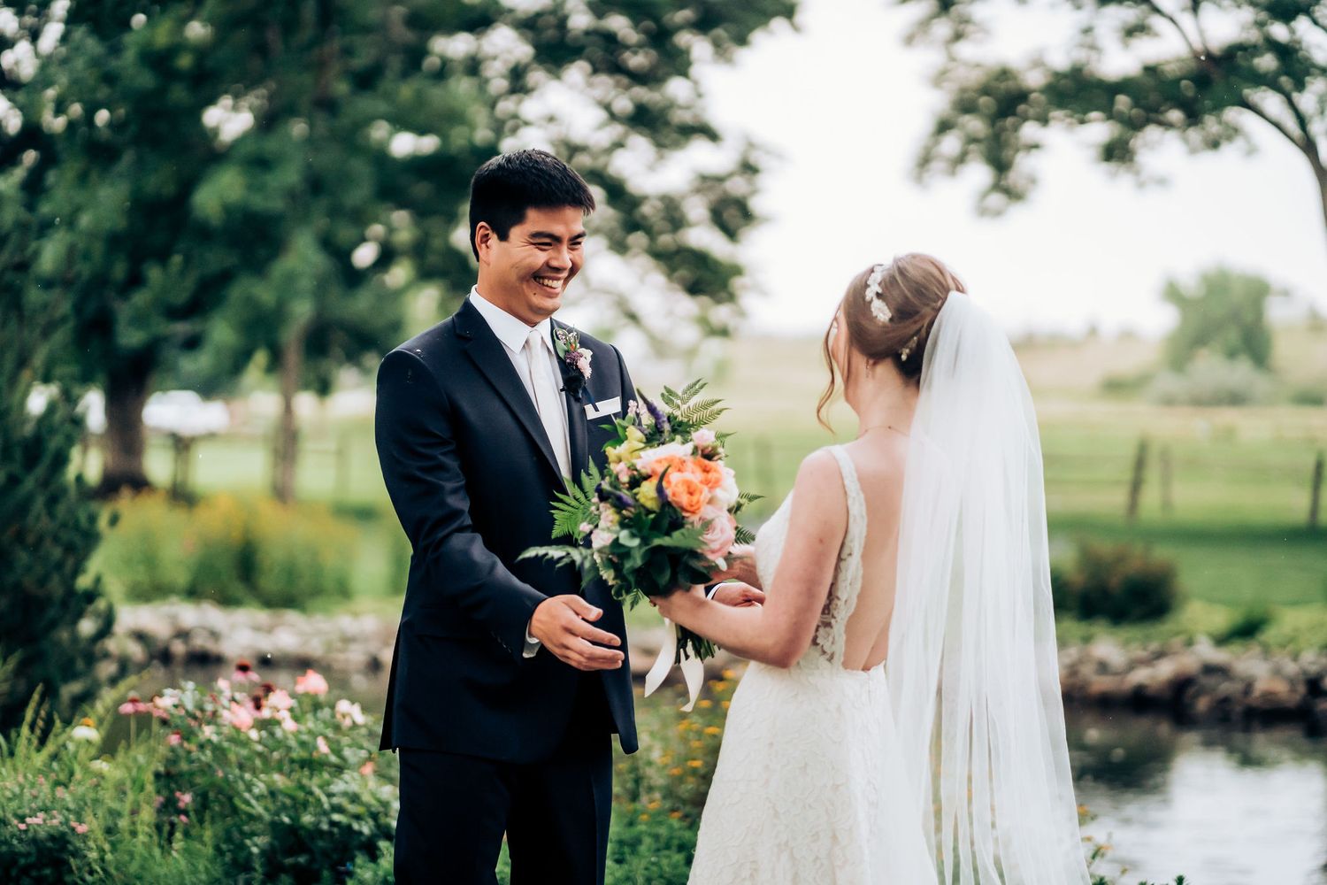 A sweet moment between newlyweds exchanging flowers in a garden setting.