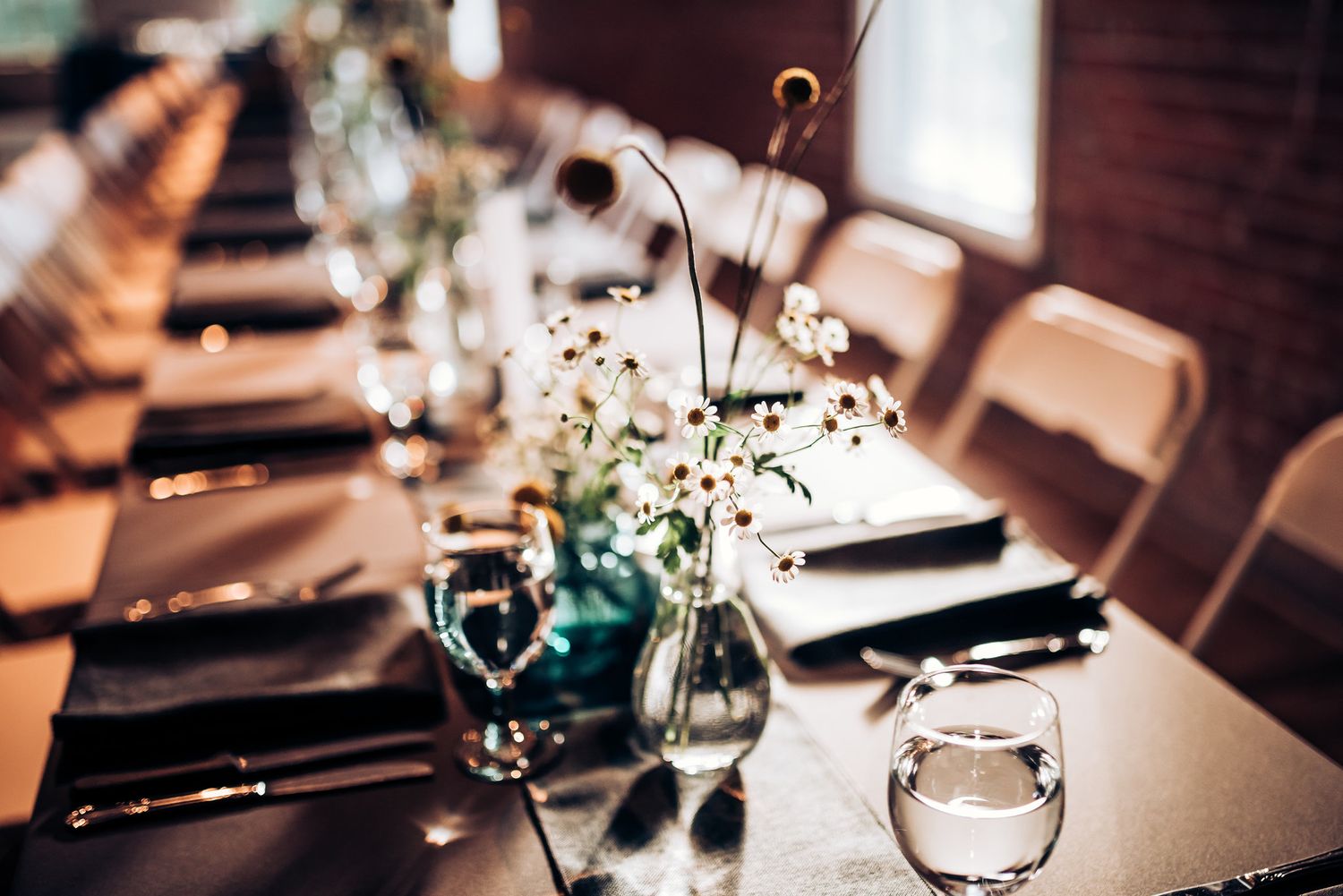 Close-up of wedding table settings with delicate baby's breath flowers in glass vases and wine glasses.