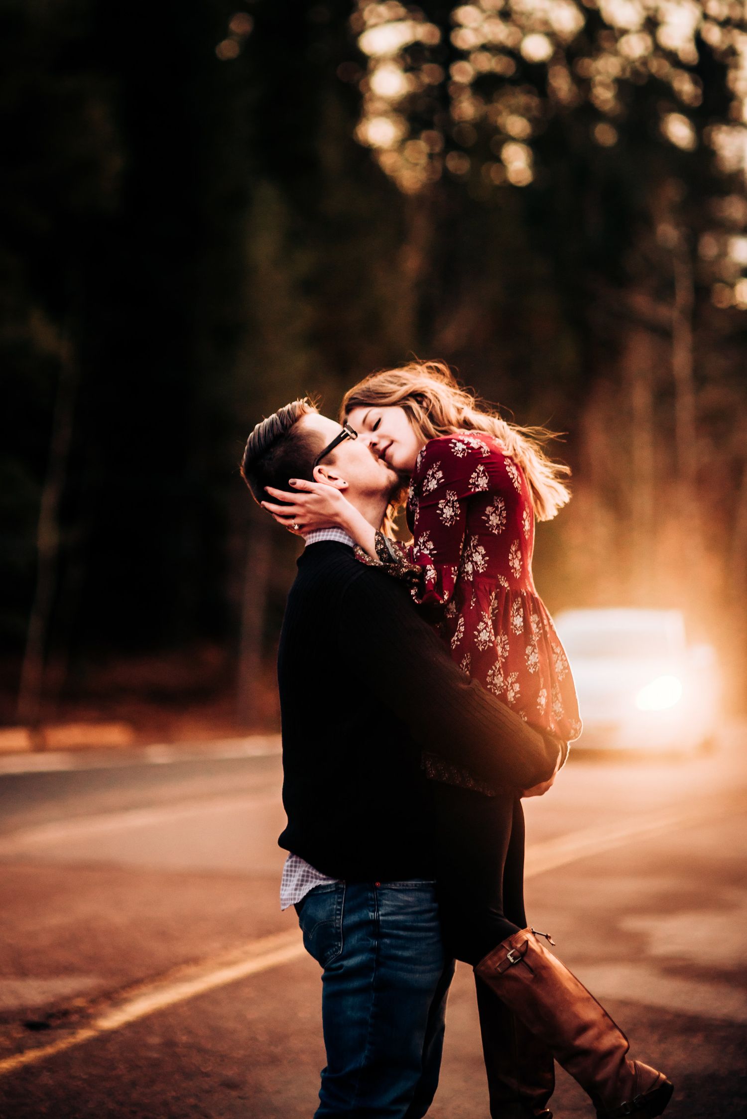 Romantic sunset embrace on rural road with warm backlighting.