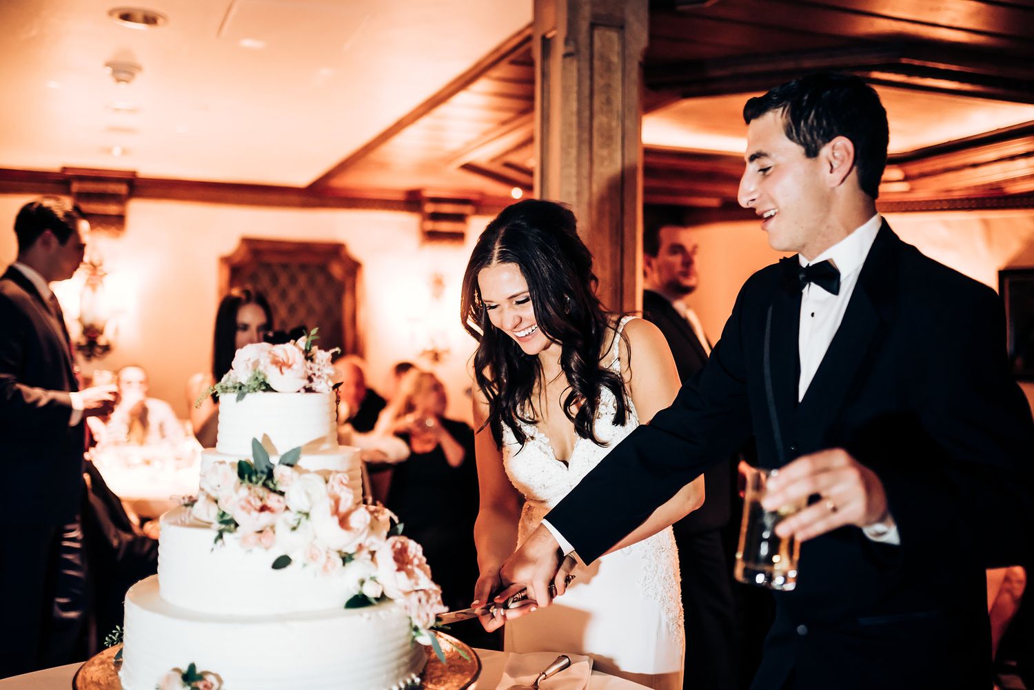 Wedding couple cuts their elegant white tiered cake during the reception celebration.