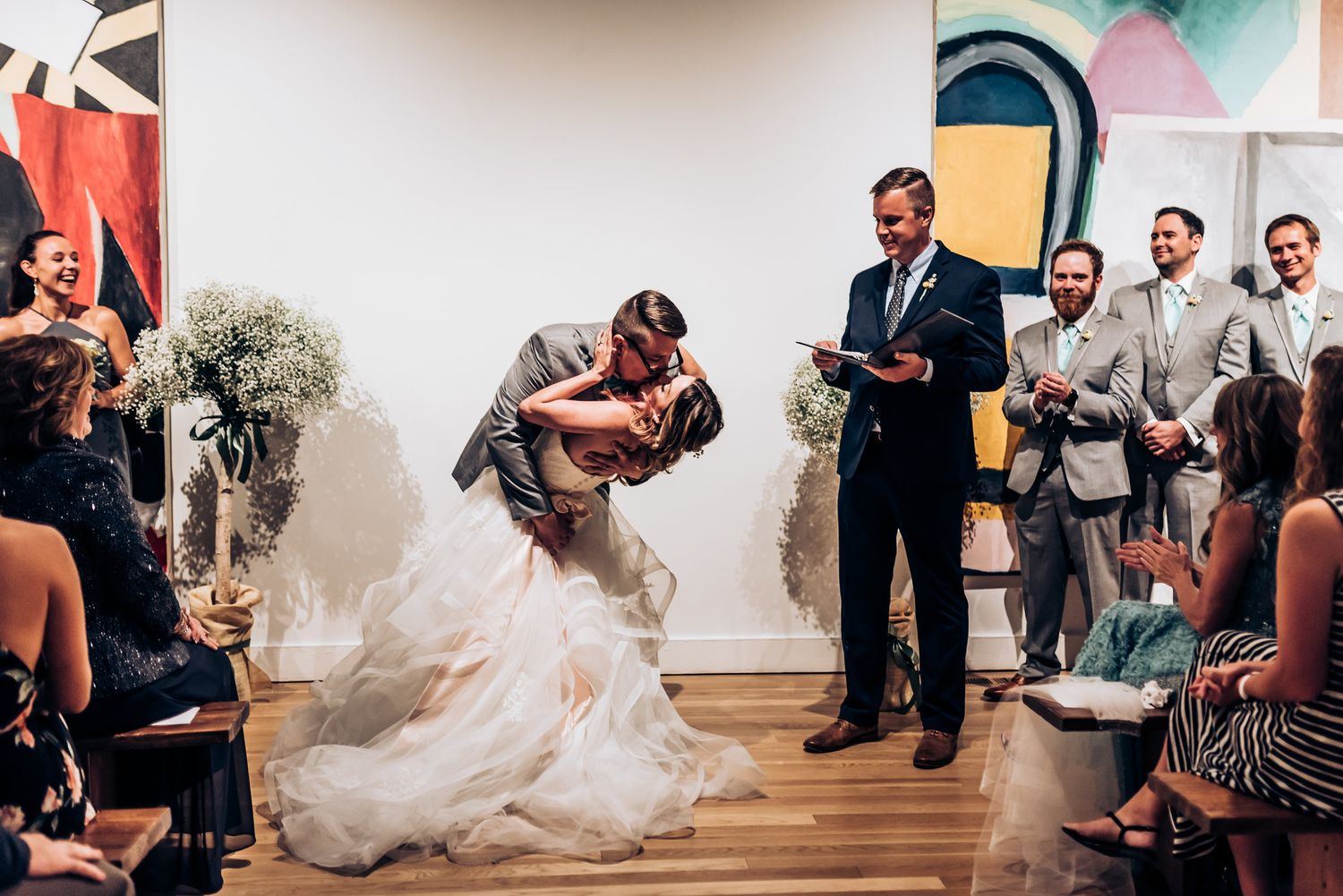 Romantic first kiss as newlyweds during art gallery wedding ceremony.
