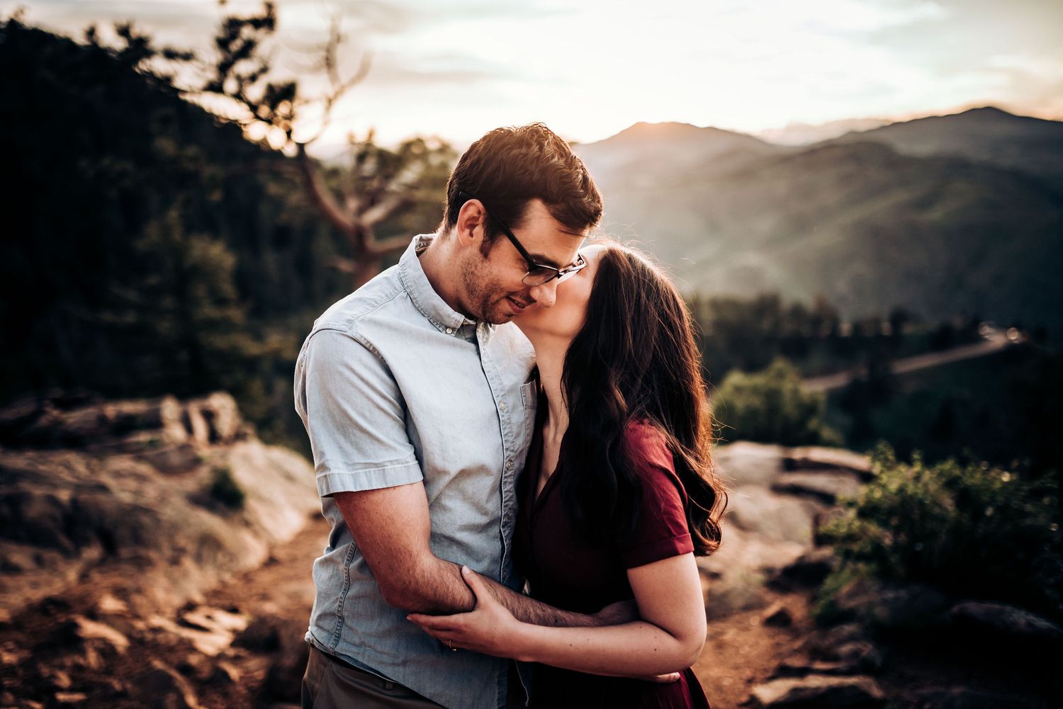 Intimate embrace between couple on mountain overlook during sunset.
