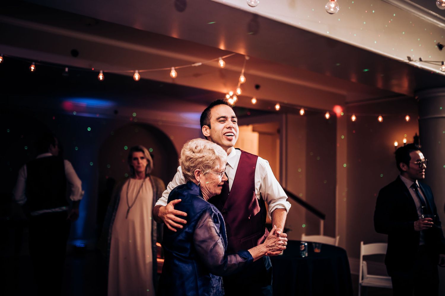 Guests sharing a dance at an elegant indoor wedding reception with mood lighting.