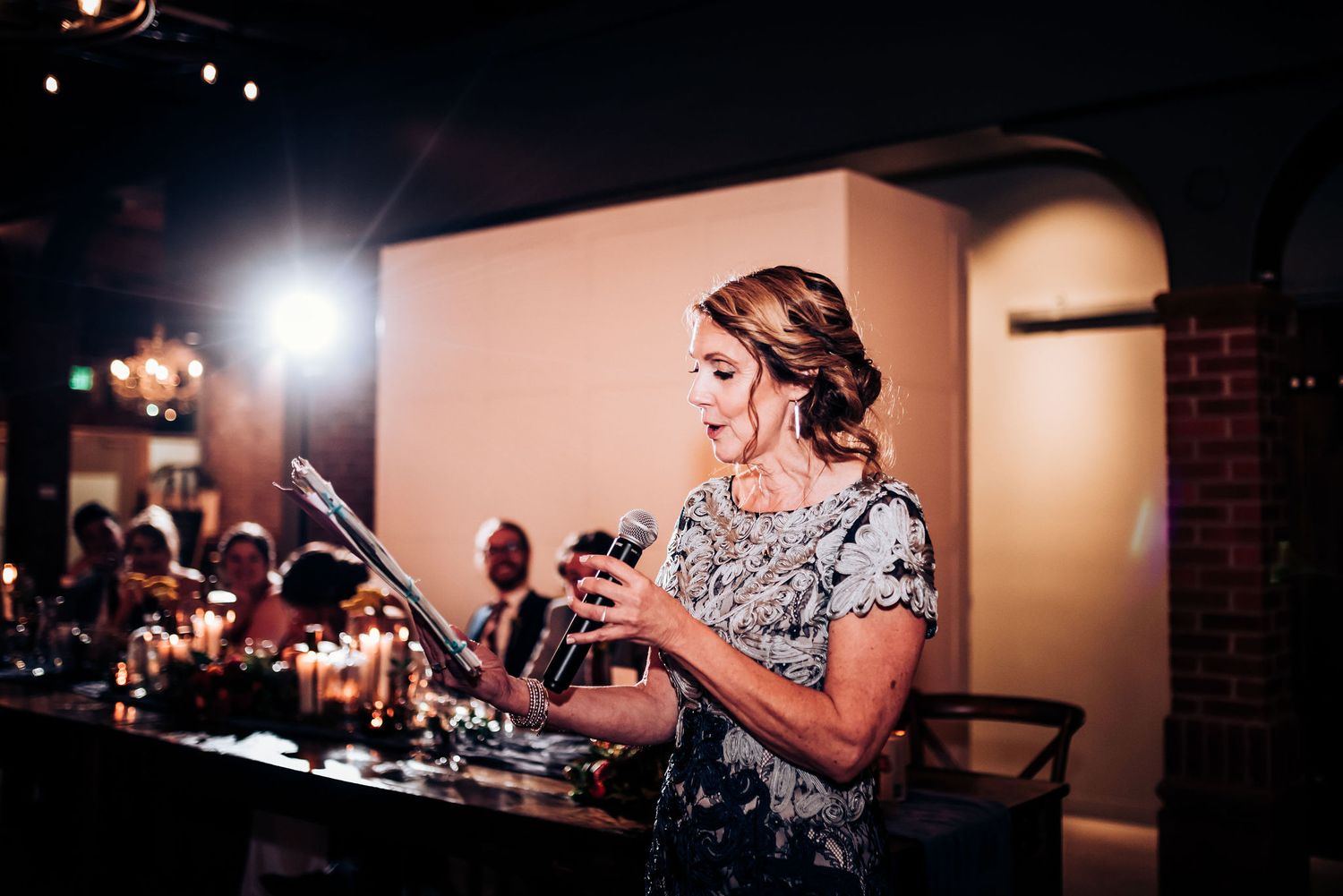 Speaker in floral dress delivers speech at evening reception.
