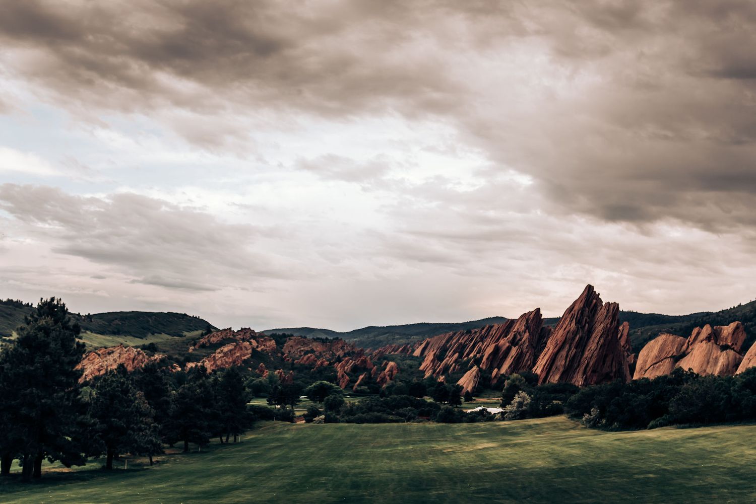 Dramatic landscape view of red rock formations under cloudy skies in Colorado.