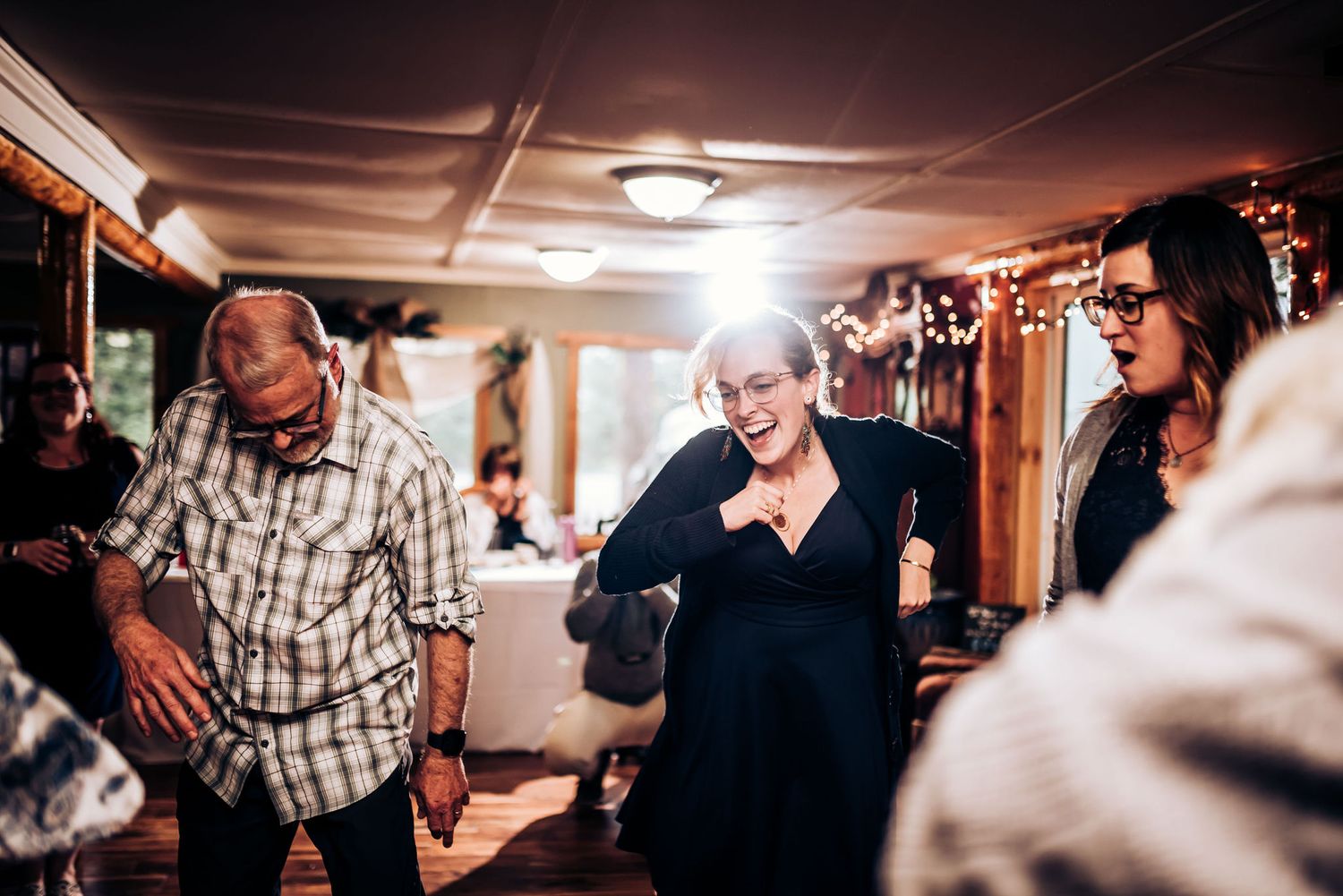 People laughing and dancing together at an indoor celebration.