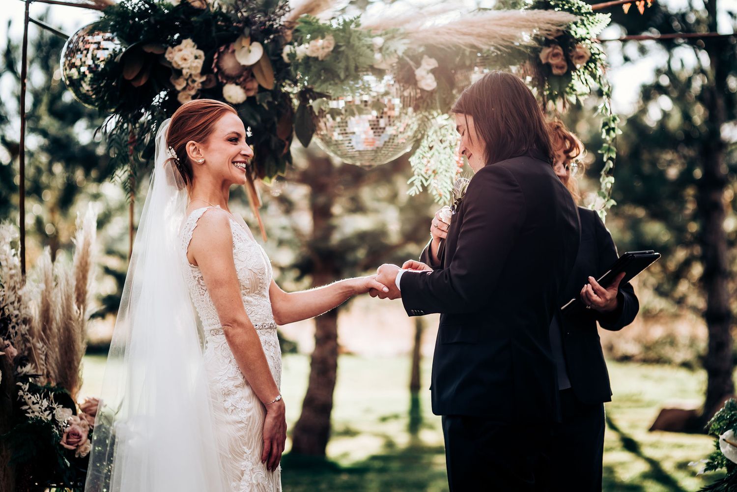 Happy couple sharing a candid moment during their wedding ceremony under a floral arch.