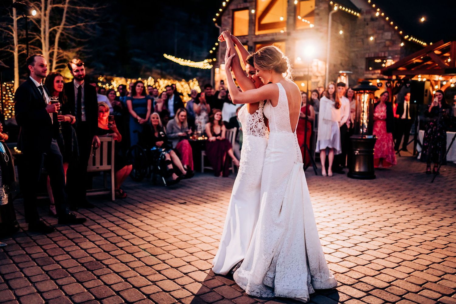 Intimate wedding dance captured on brick patio with warm lighting and guests watching.