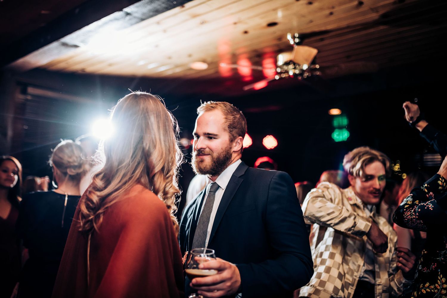 Party guests mingling and socializing at a dimly lit indoor venue.