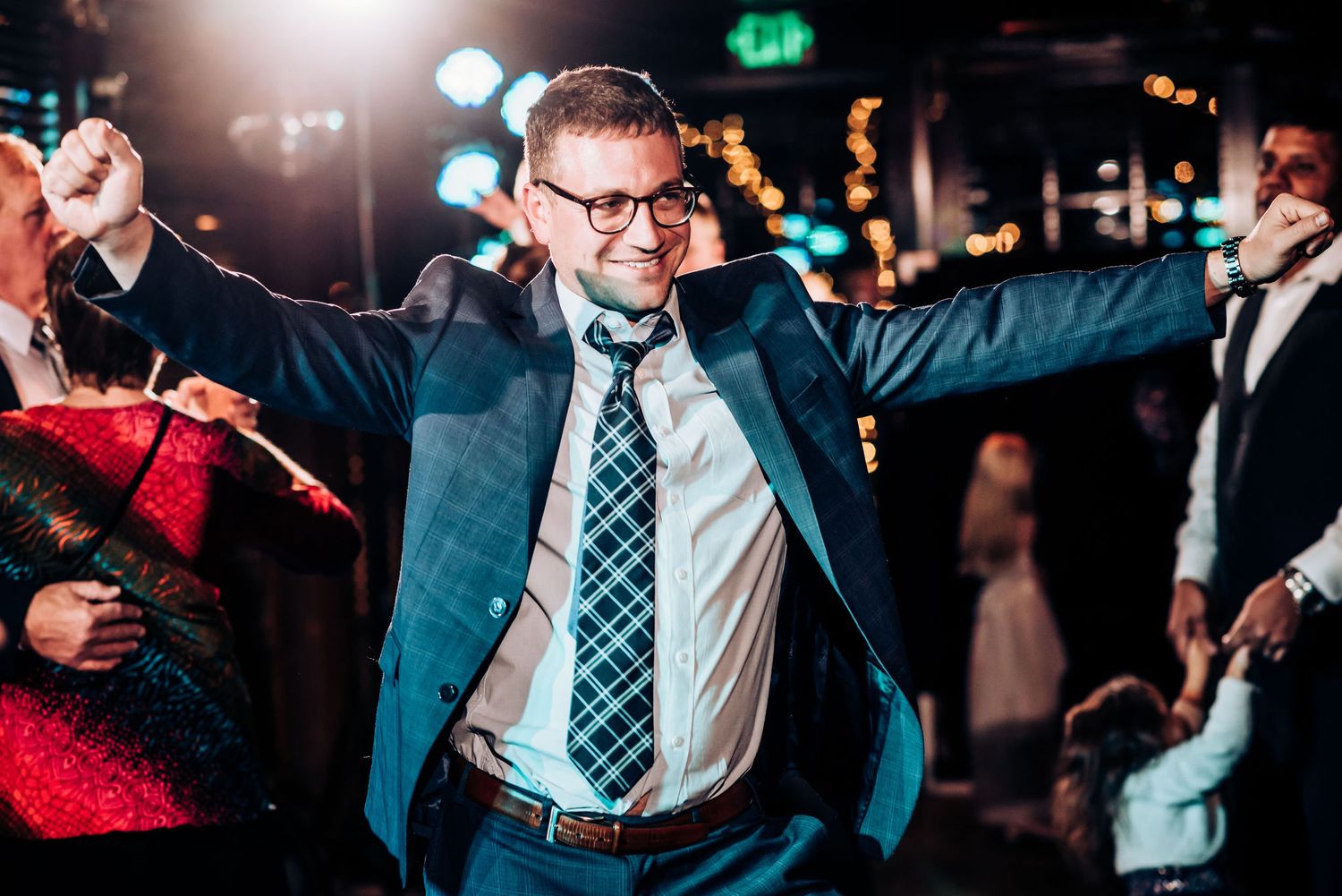 A guest celebrates with enthusiasm on the dance floor wearing a suit and tie.