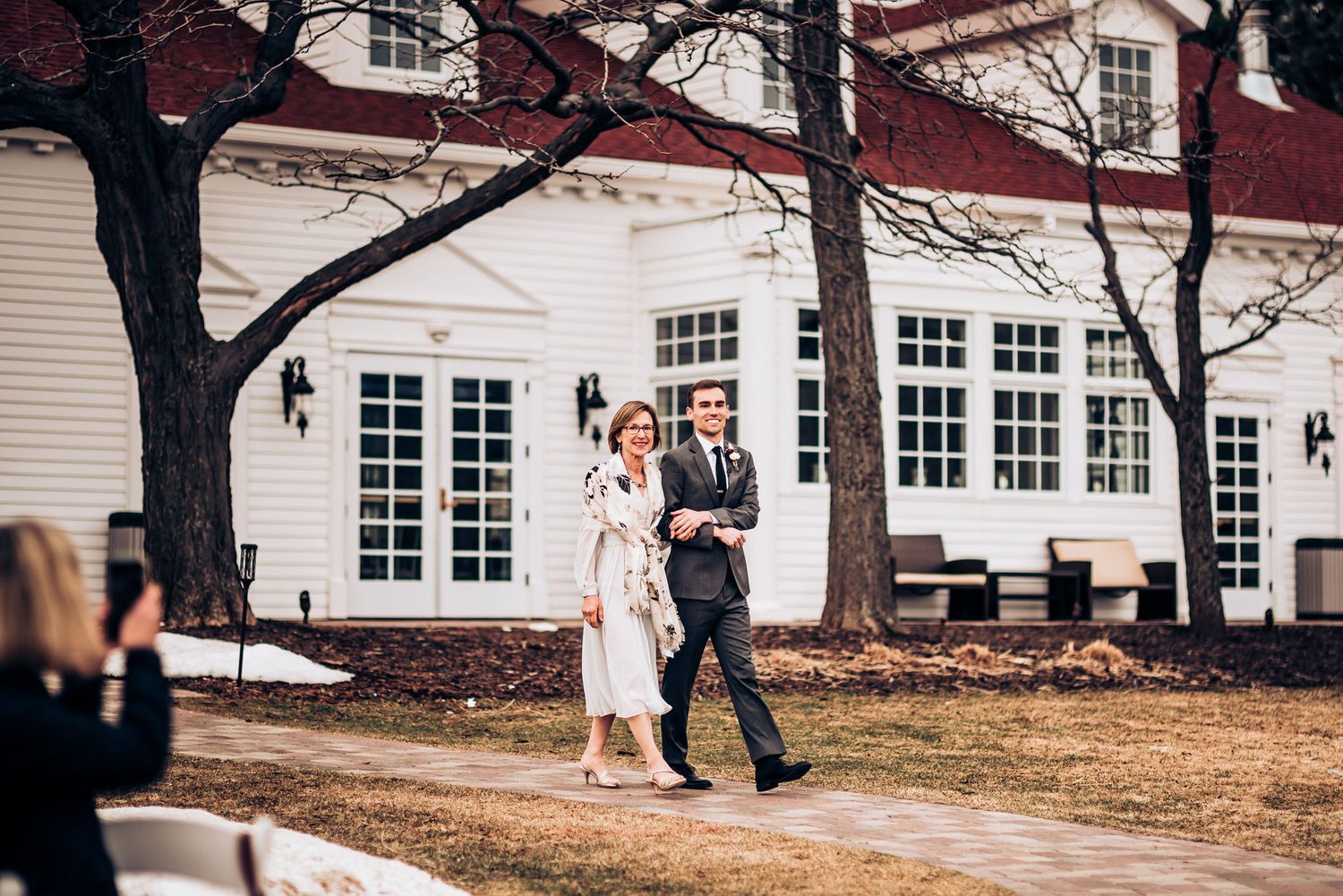 Elegant couple walking outside a classic white colonial style building on a winter day.
