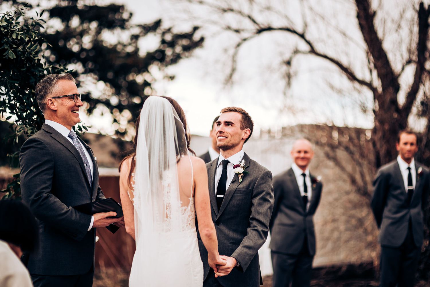 Wedding ceremony on a patio with a celebrant and wedding party in formal attire.