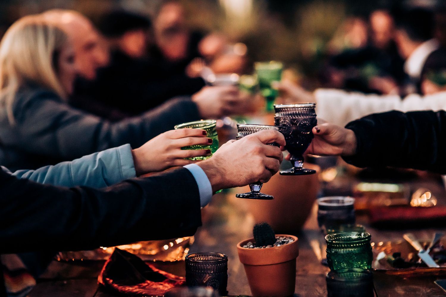 Guests toasting with wine glasses at outdoor desert dinner party.