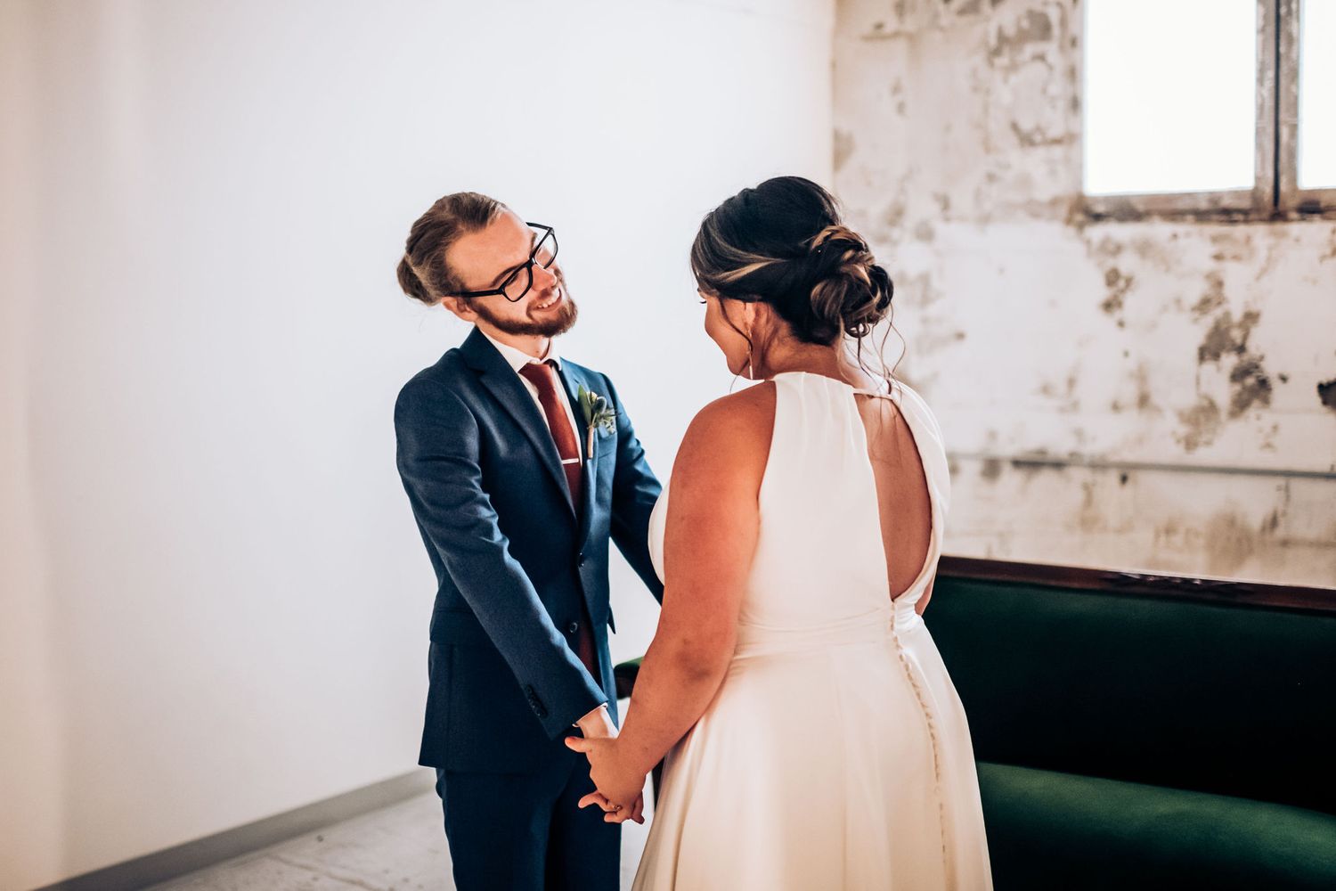 A tender moment shared between newlyweds in a rustic room with a green velvet couch and weathered walls.