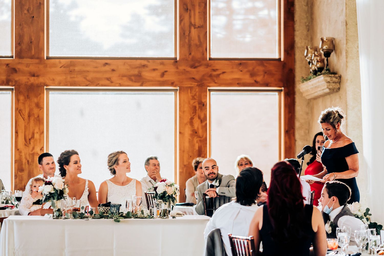 Wedding reception scene with rustic wood details and elegant table settings.