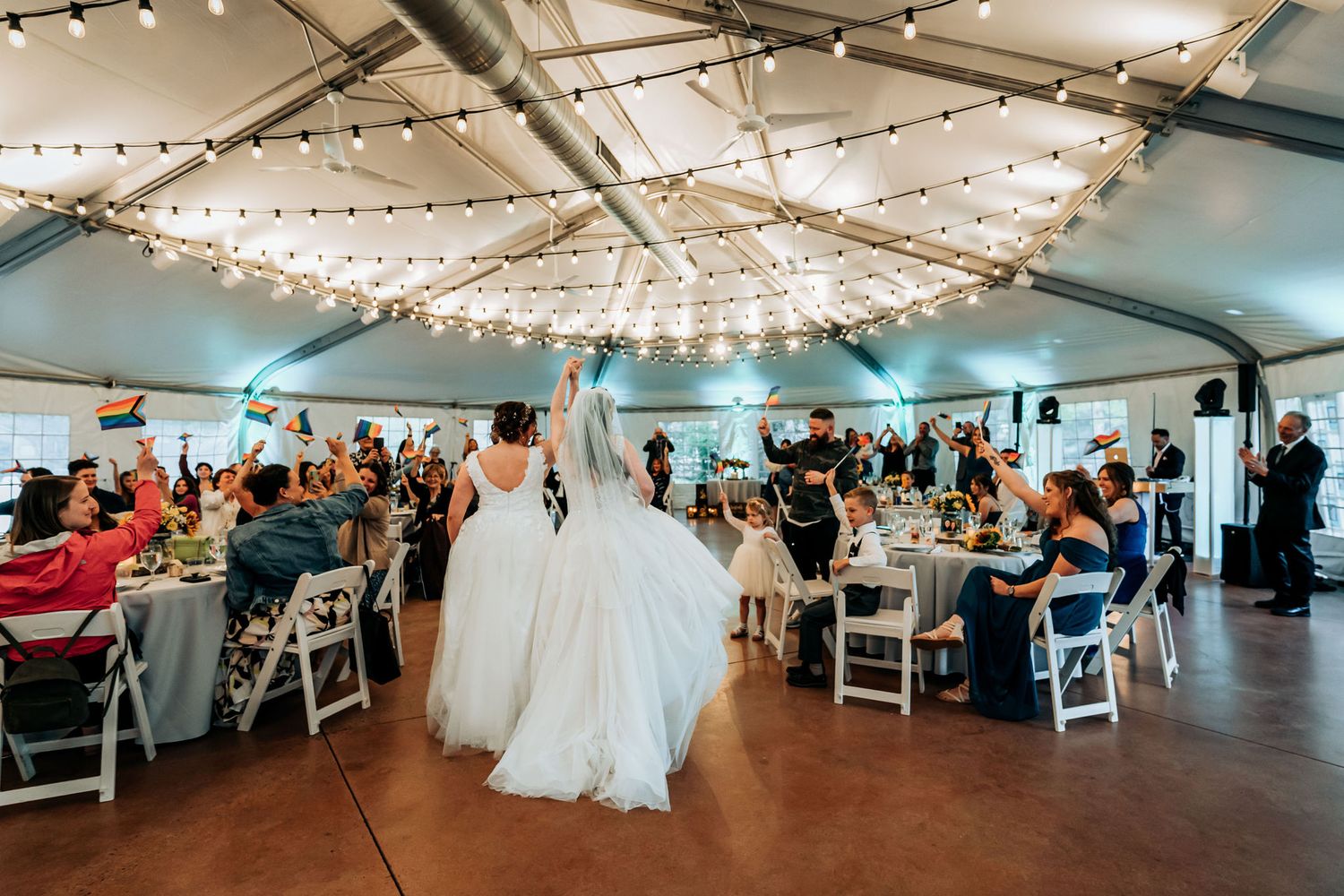 Reception venue with string lights and white chairs set up for wedding guests.