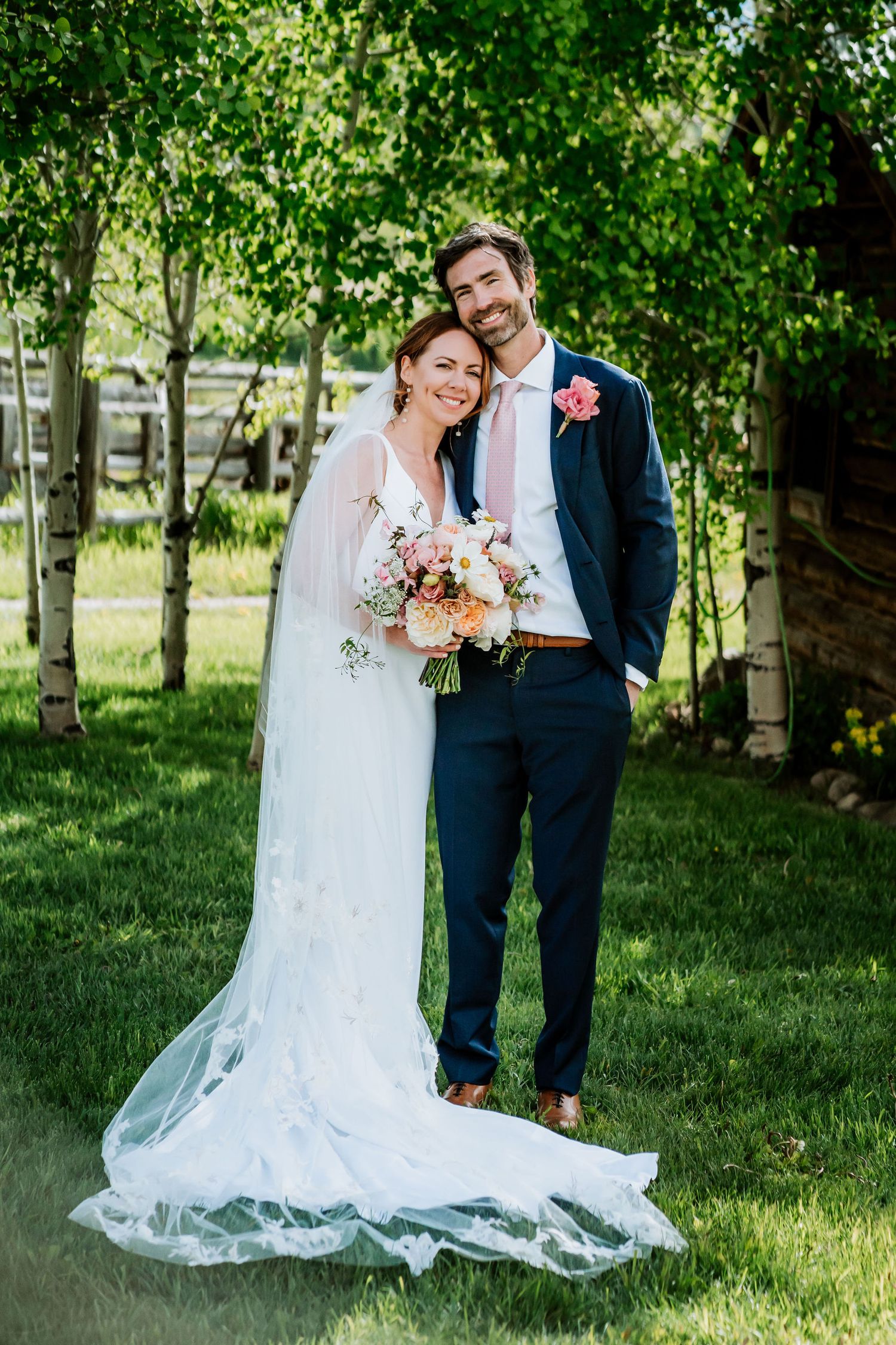 Spring wedding portrait in birch grove with elegant white gown and navy suit.