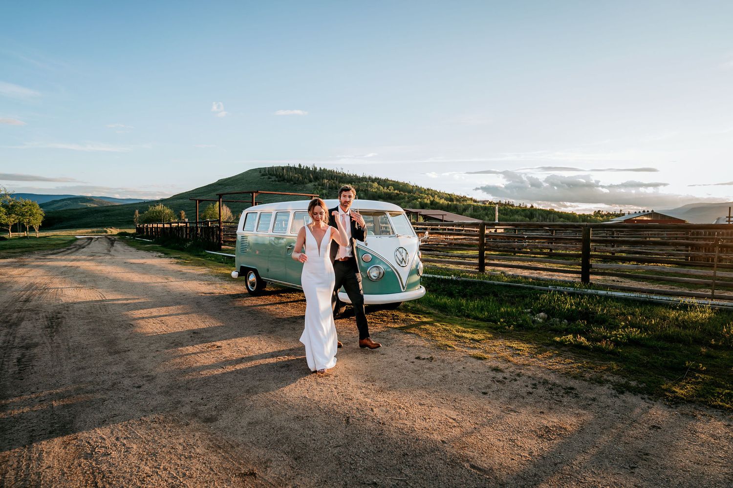A sunset wedding portrait with a classic teal Volkswagen bus on a dirt road.