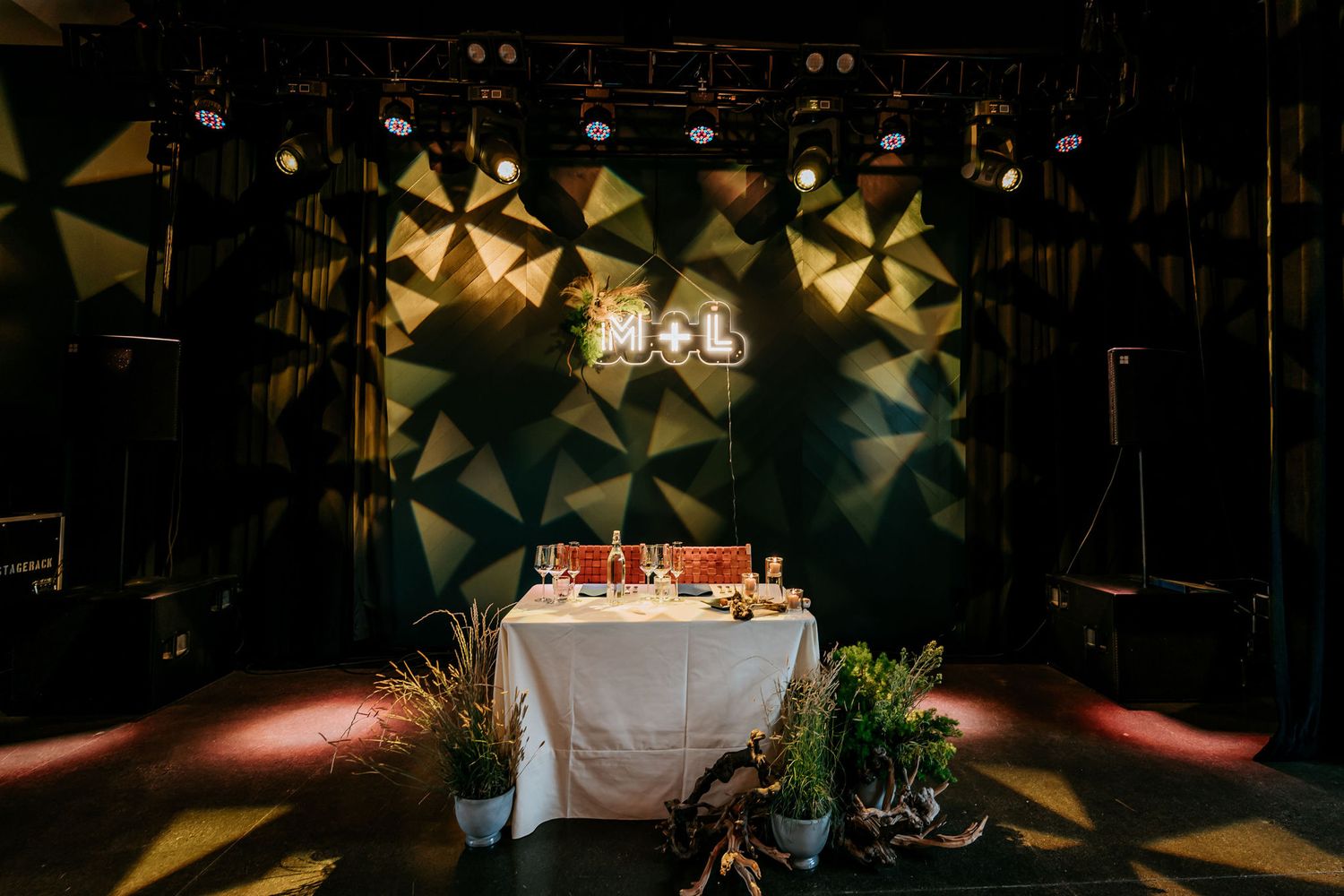 Wedding reception table setup with geometric lighting design and white tablecloth.