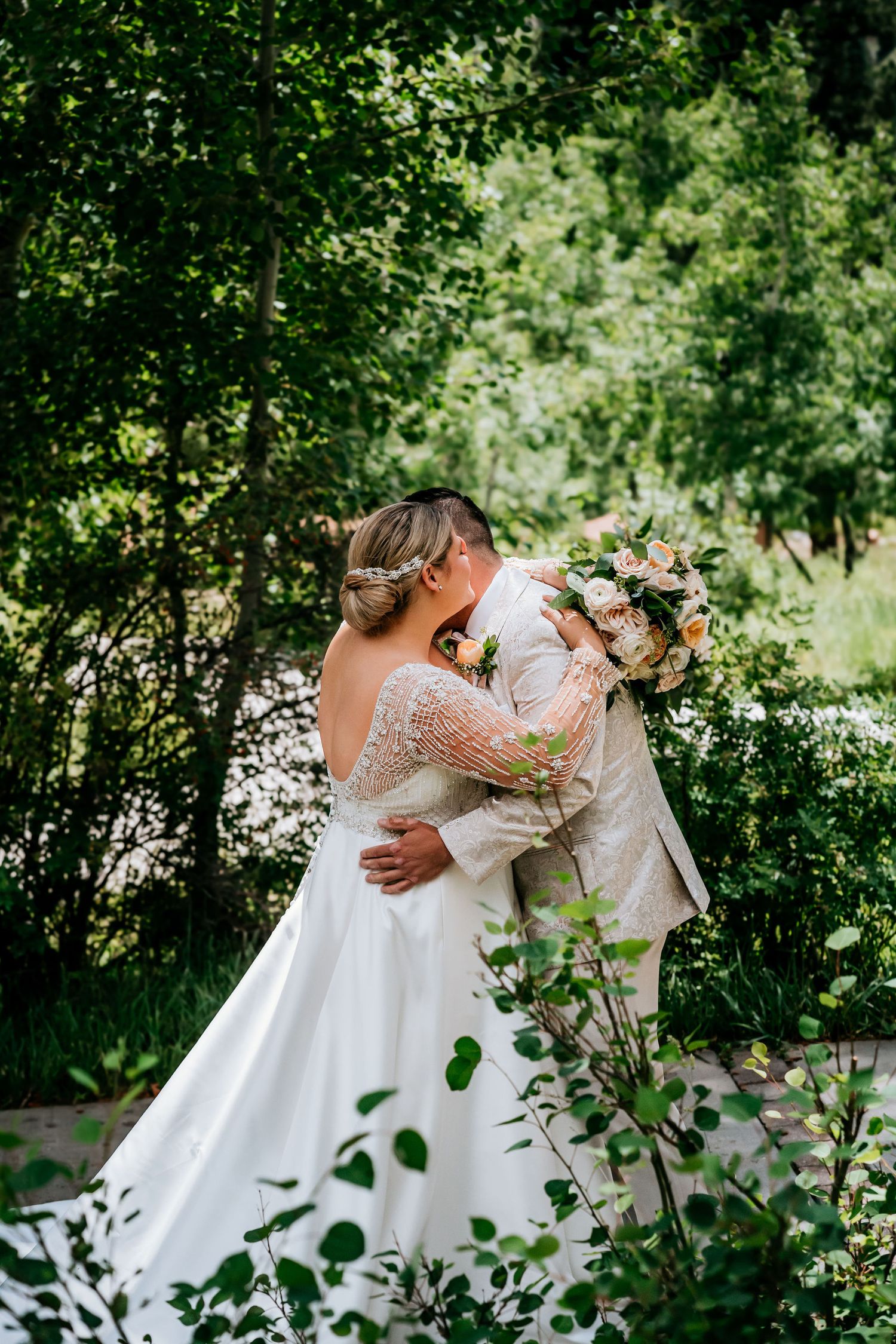 Wedding couple shares intimate moment in garden setting surrounded by greenery.