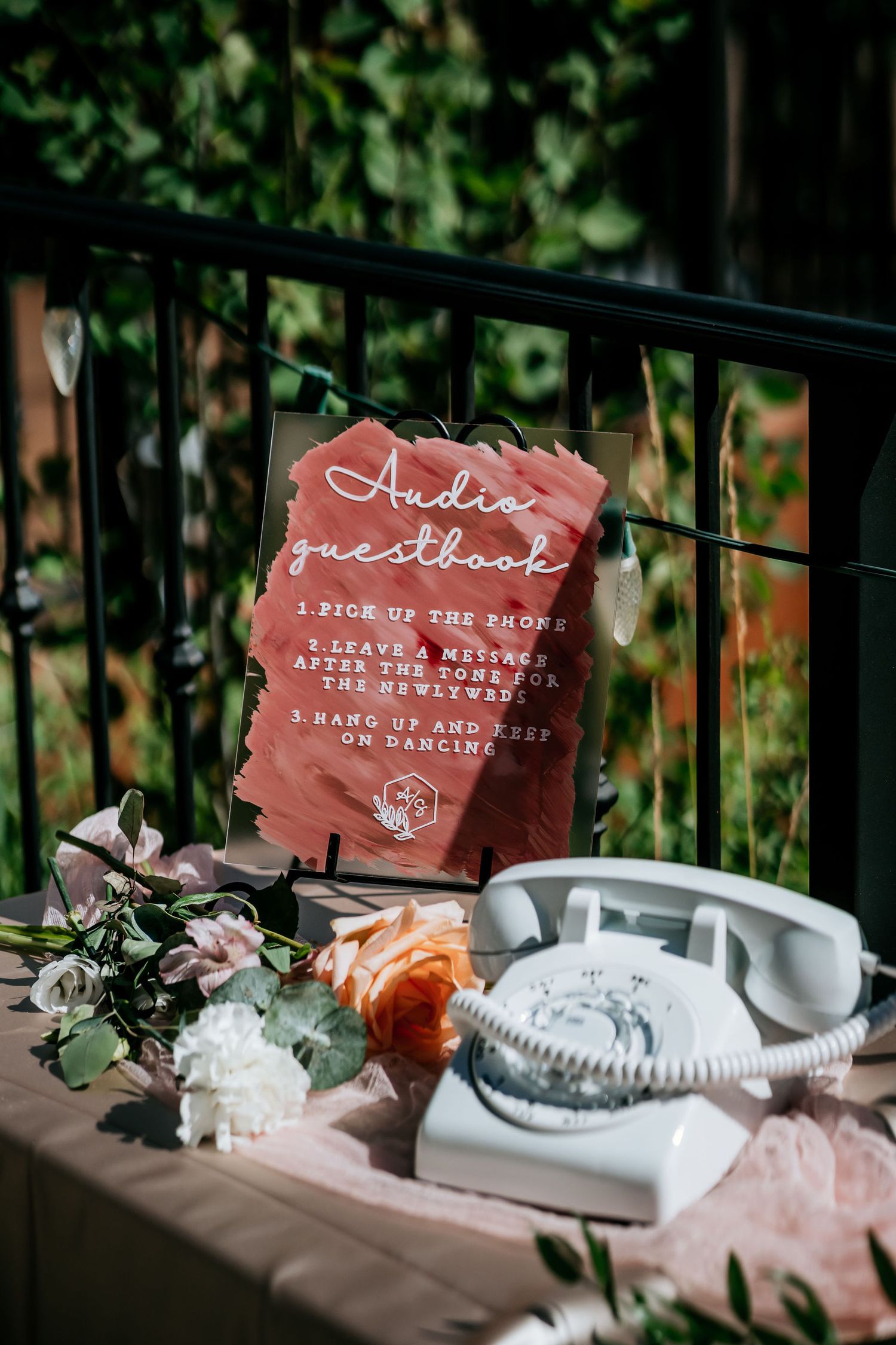 Vintage rotary phone and wedding signage displayed with flowers on a decorative table.