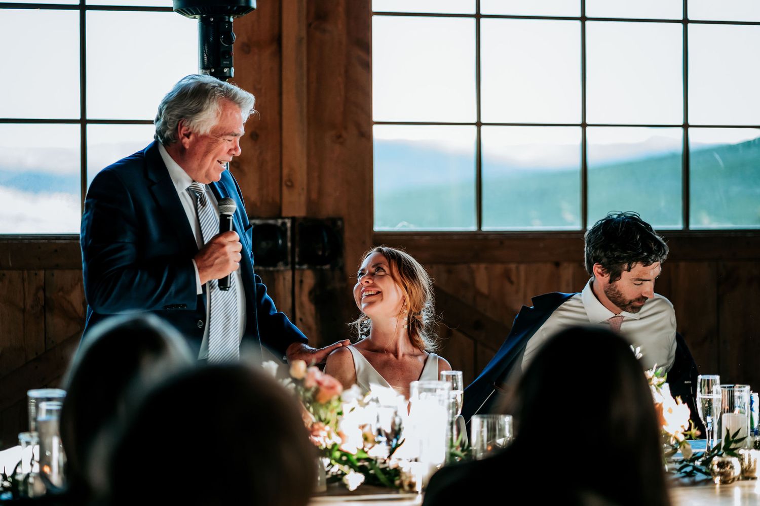 An emotional moment captured during wedding speeches in a mountain lodge reception venue.