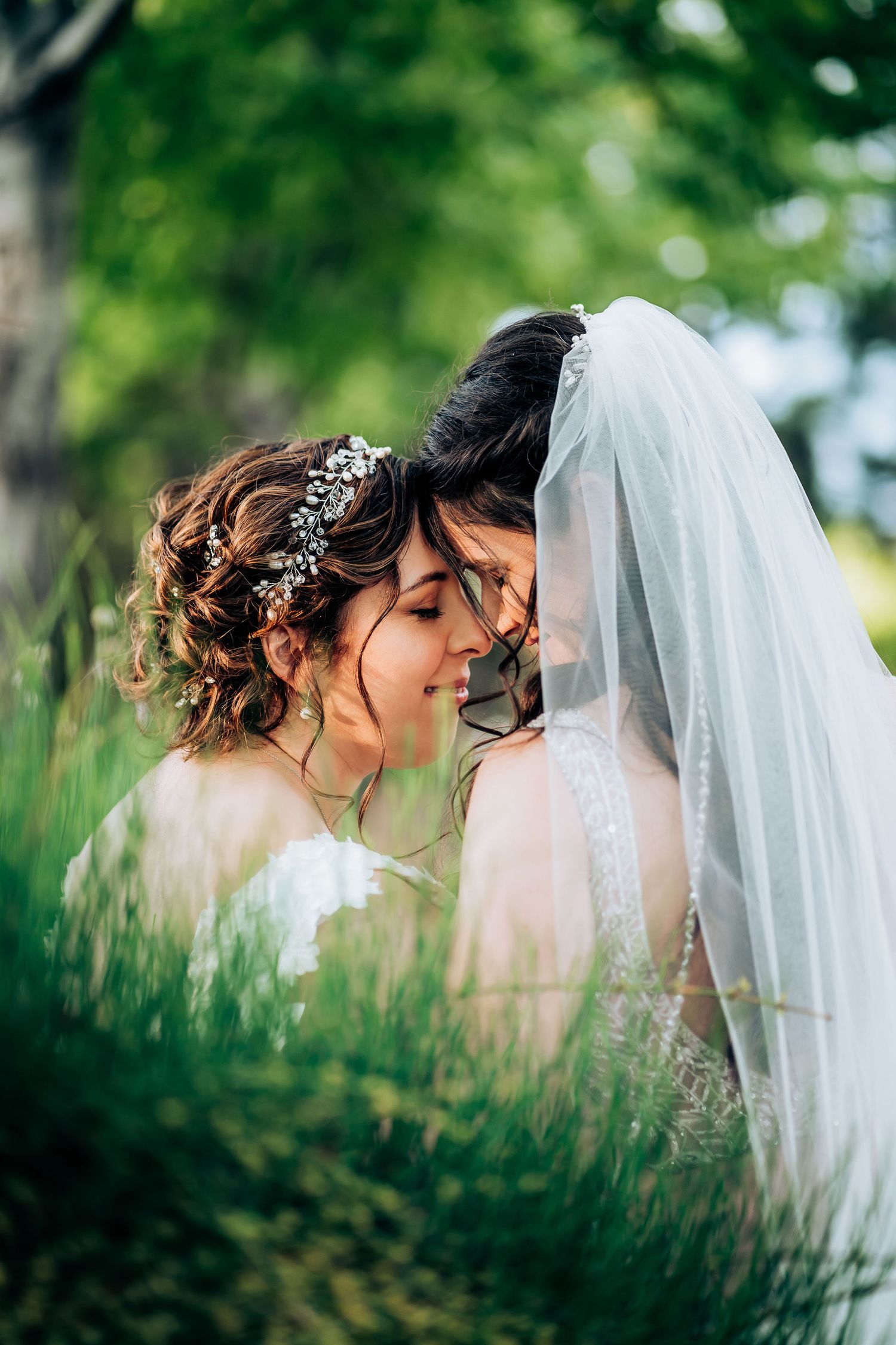 Intimate wedding moment captured in tall grass with soft natural lighting.