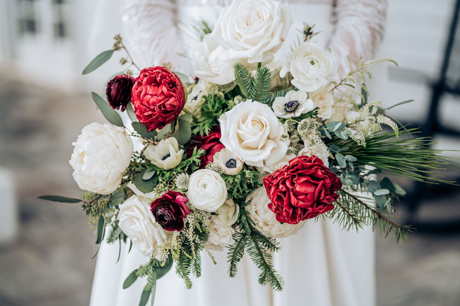 Elegant wedding bouquet featuring red and white roses with mixed greenery.