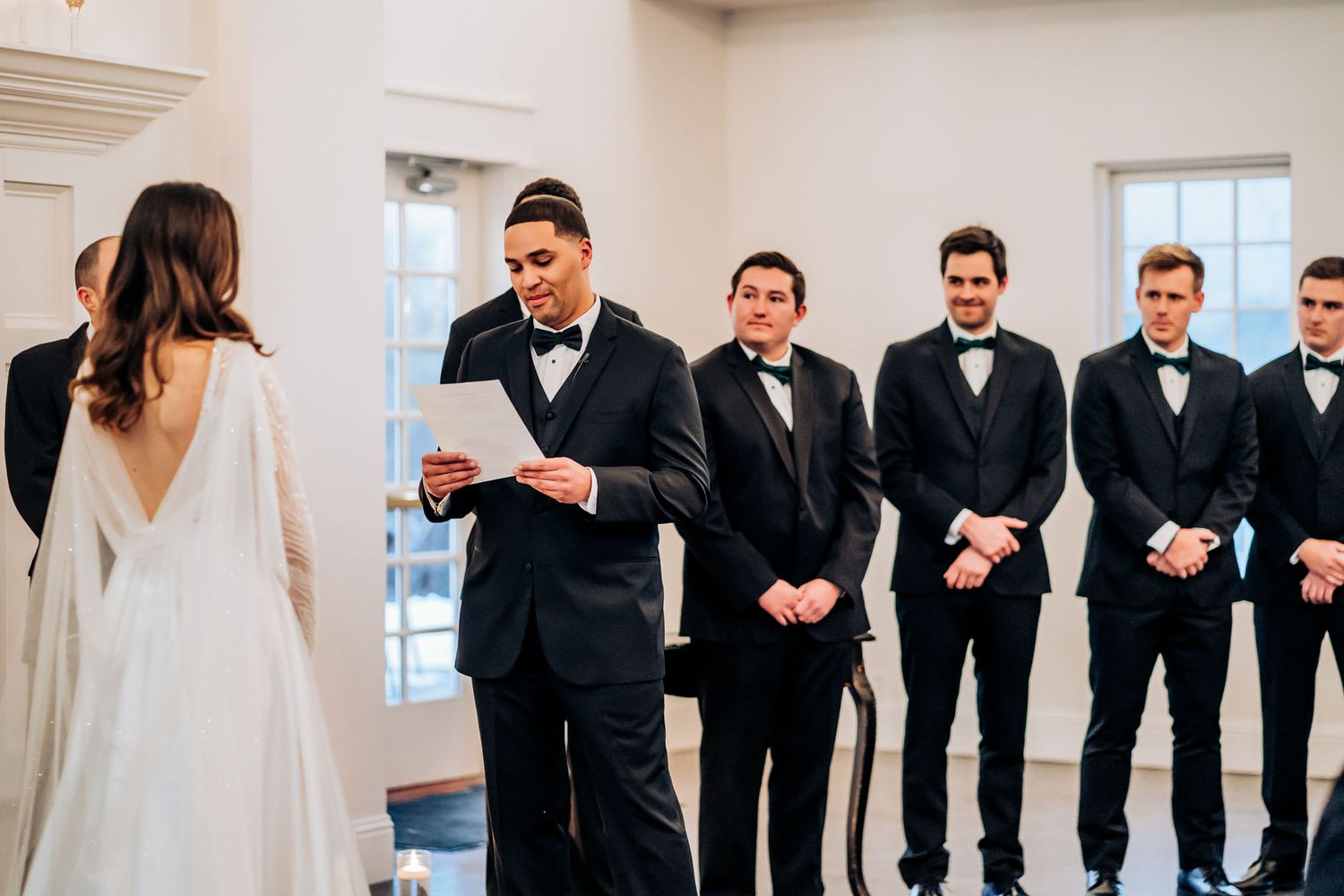 The couple shares a moment during their wedding ceremony while the wedding party looks on.