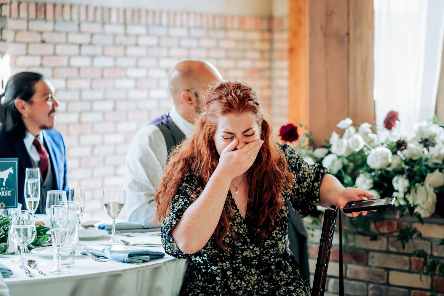 Guest reacts emotionally during wedding reception speeches at decorated table.