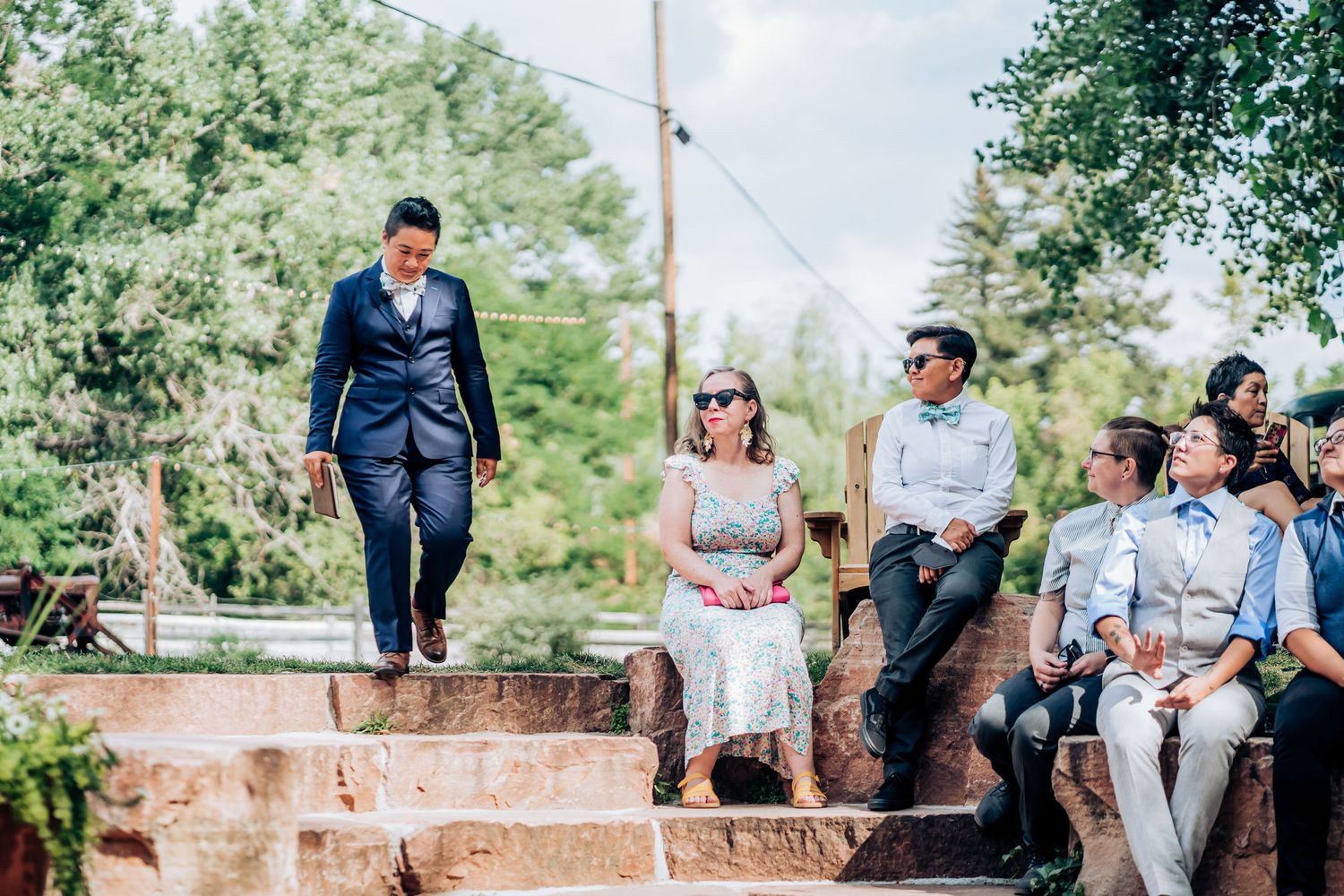 Wedding guests gather on rustic stone steps during an outdoor celebration.