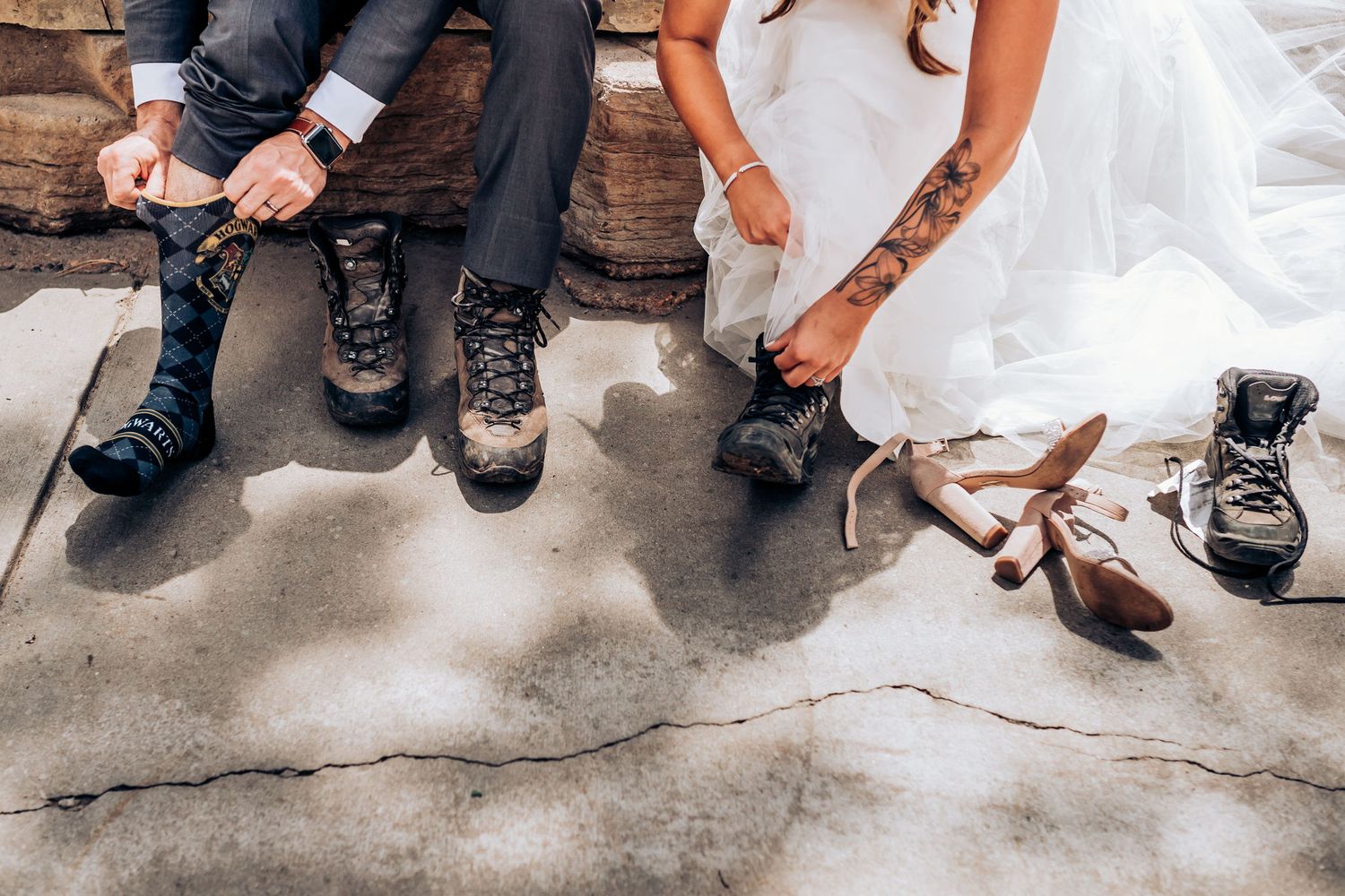Close-up of wedding couple's feet wearing hiking boots while sitting on wooden steps.