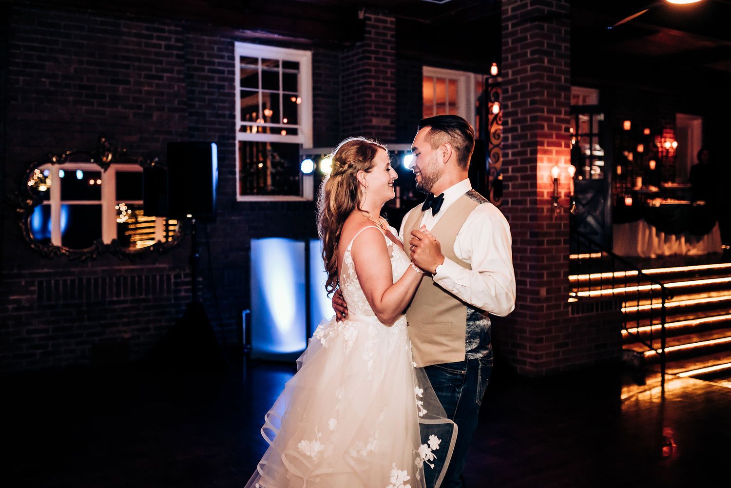 A romantic dance moment in a dimly lit brick-walled venue.