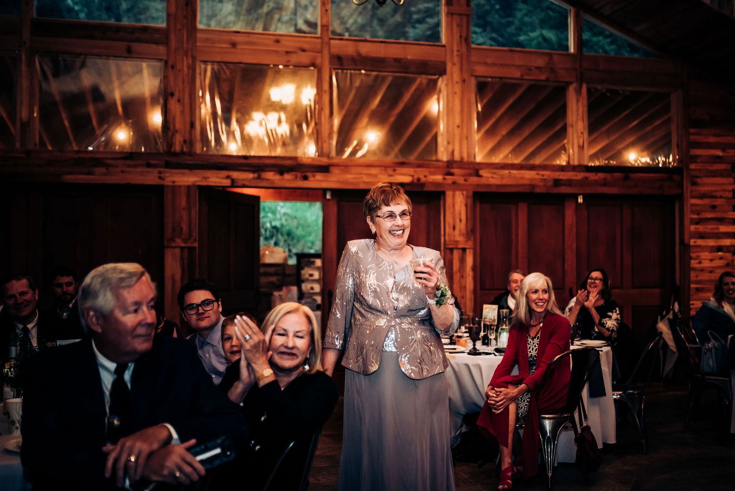 Wedding reception speech in rustic barn venue with warm ambient lighting.