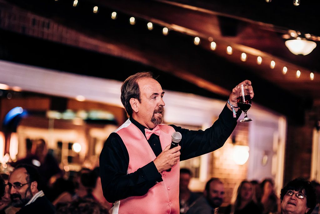 Speaker raising a glass during an indoor celebration event with ambient lighting.